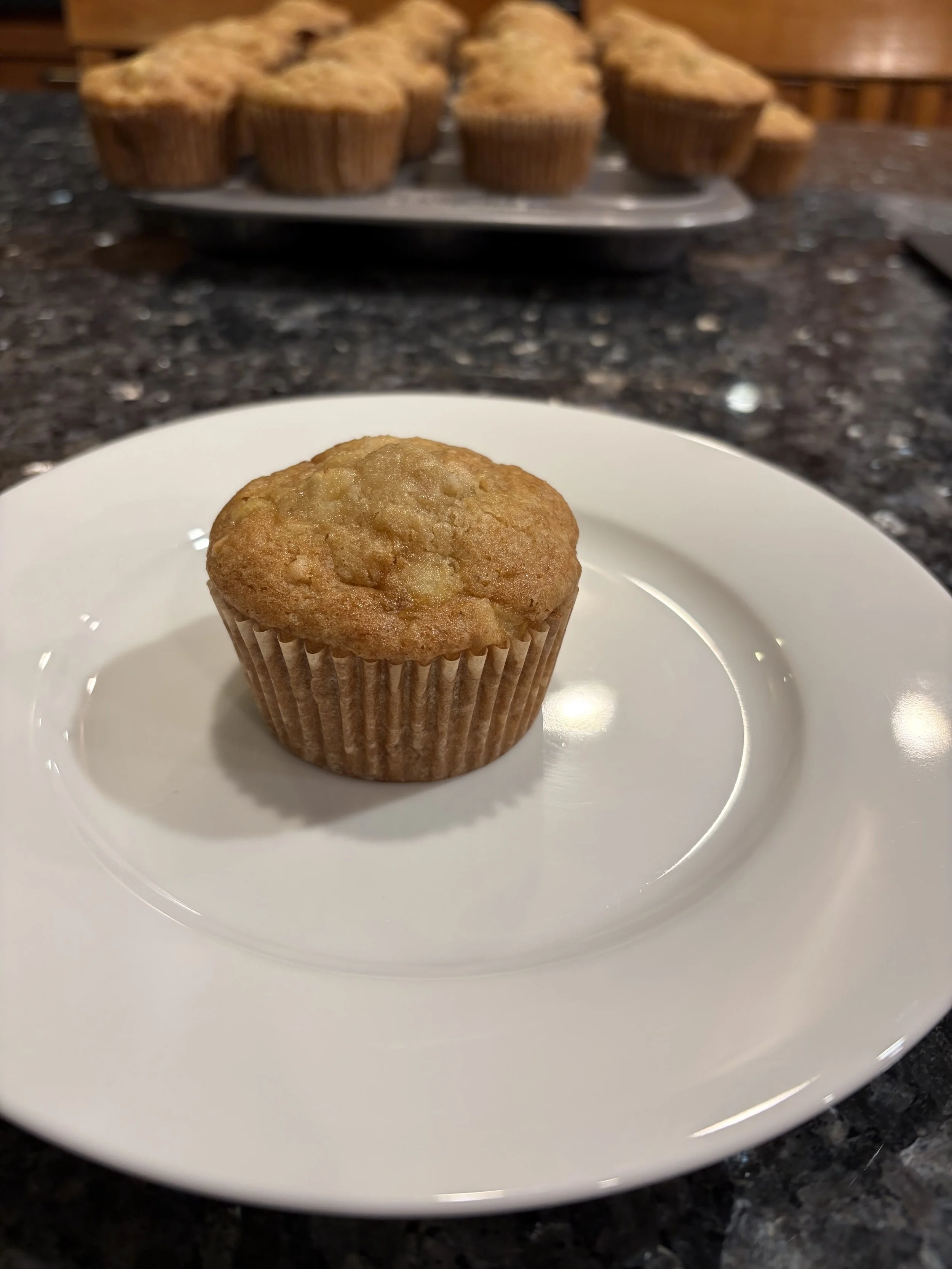 Gluten-free apple walnut muffin with a golden-brown top on a white plate.
