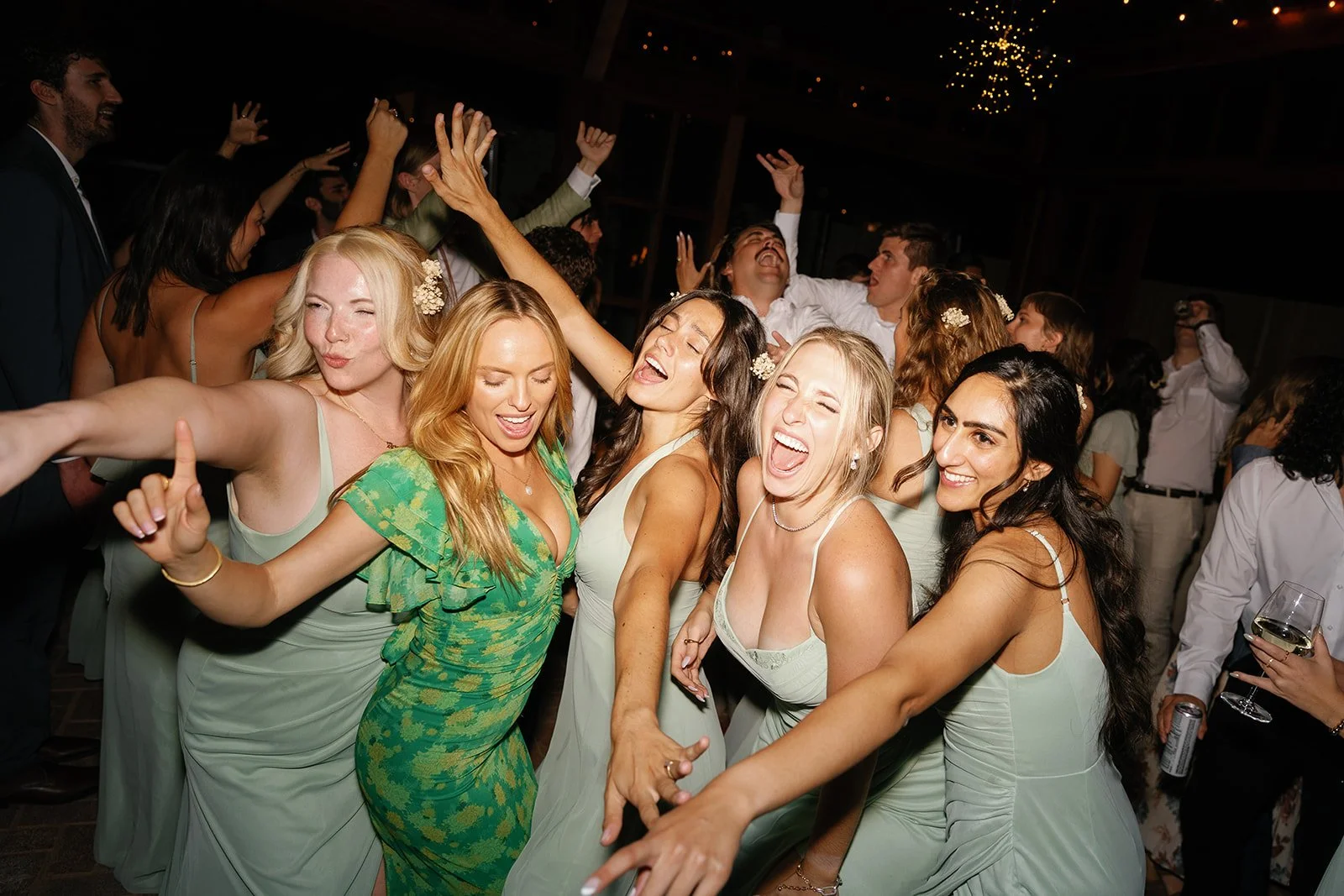Group of people dancing and celebrating at a party, wearing formal attire and enjoying themselves at a wedding