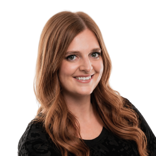 Karen, aka DJ Hemmesphere, smiling with long, wavy hair dyed in shades of blonde and purple, wearing a black patterned top, posing against a white background.