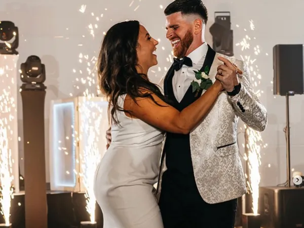 A couple dancing joyfully at a wedding, with the backdrop of sparklers and festive lighting. The man is wearing a white and black suit with a bow tie, while the woman is in a light-colored dress at Clayton House in Scottsdale, Arizona