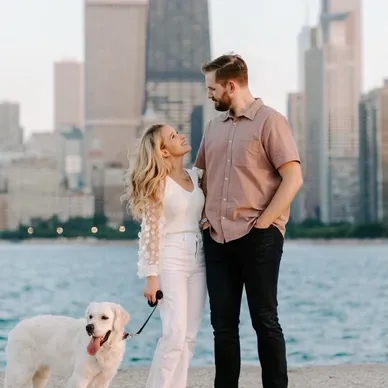 Couple with a dog by the waterfront with city skyline backdrop