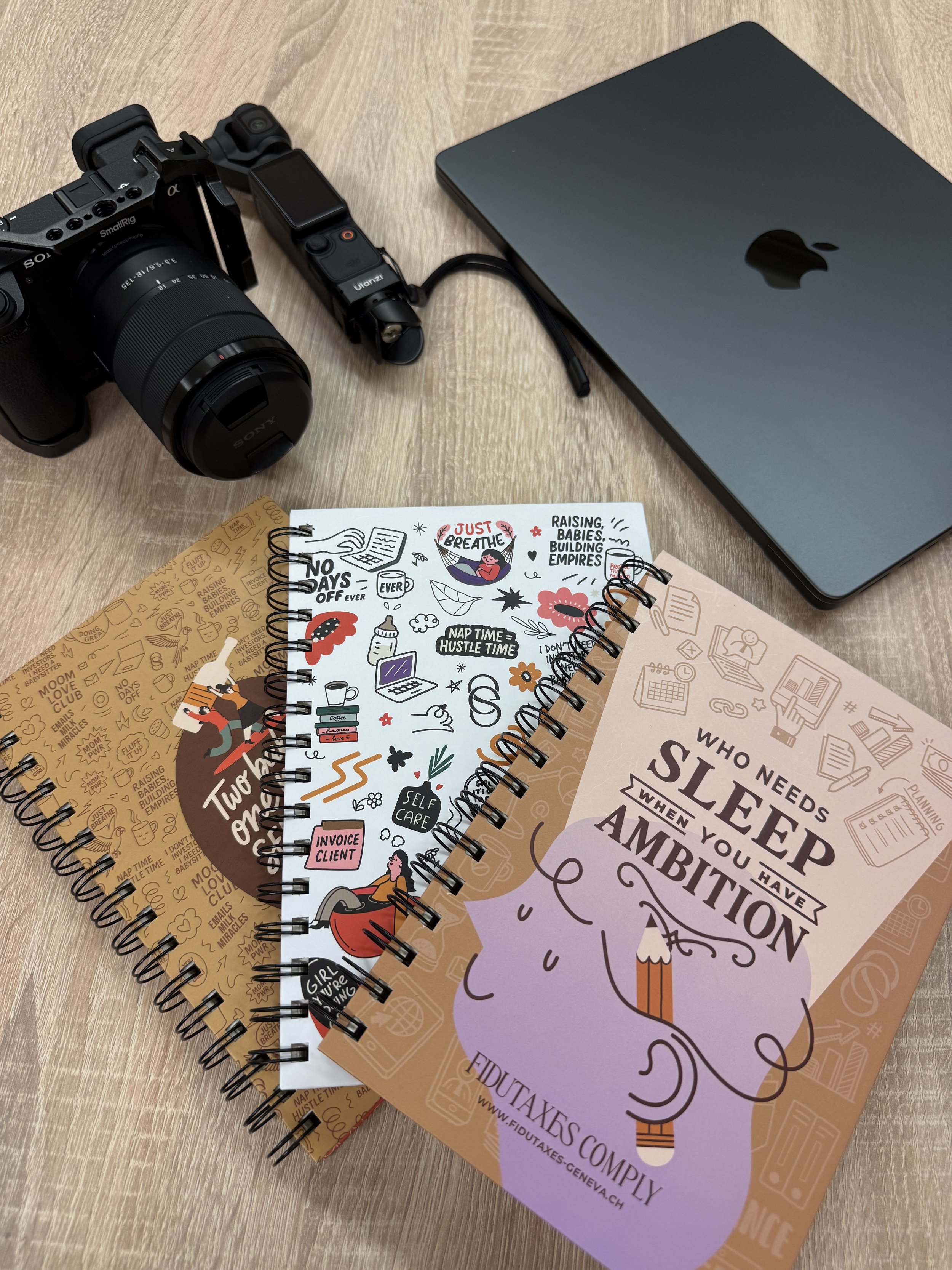 Un ordinateur portable, une caméra Sony, osmo pocket 3, un carnet avec une citation sur le sommeil et l'ambition. La vie d'entrepreneur