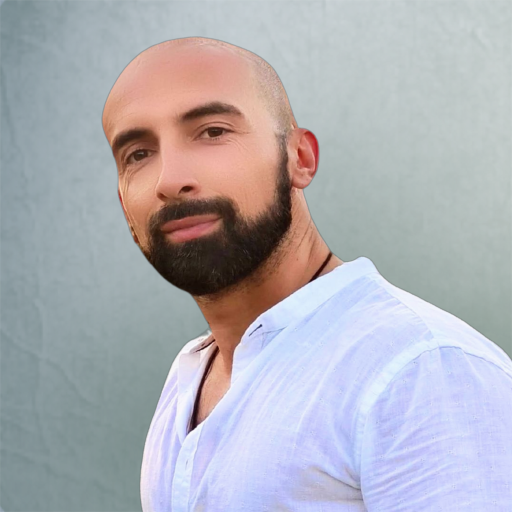 Uomo con barba cortissima e testa rasata, che indossa una maglietta bianca, sfondo grigio