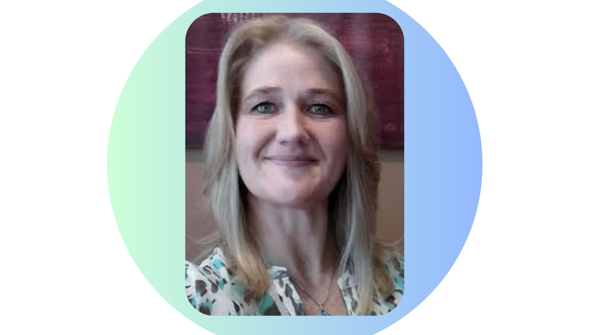 Close-up of a smiling woman with blonde hair, wearing a patterned blouse, in front of a colorful background.