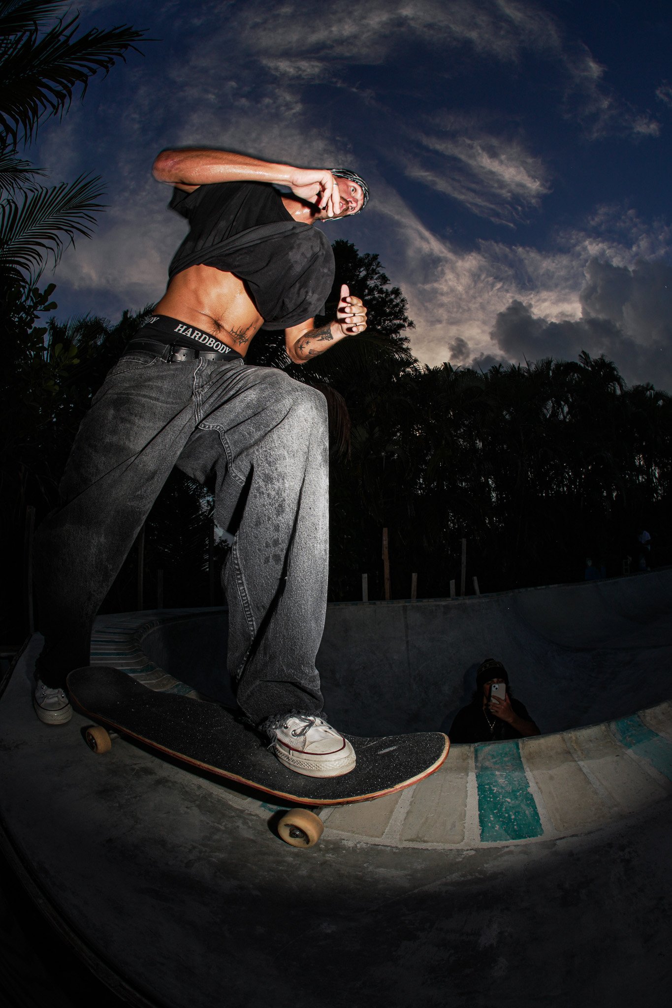 Professional skateboarder Nick Day performing a frontside grind in a backyard skate bowl during a commercial action sports production captured by Threadline Collective.