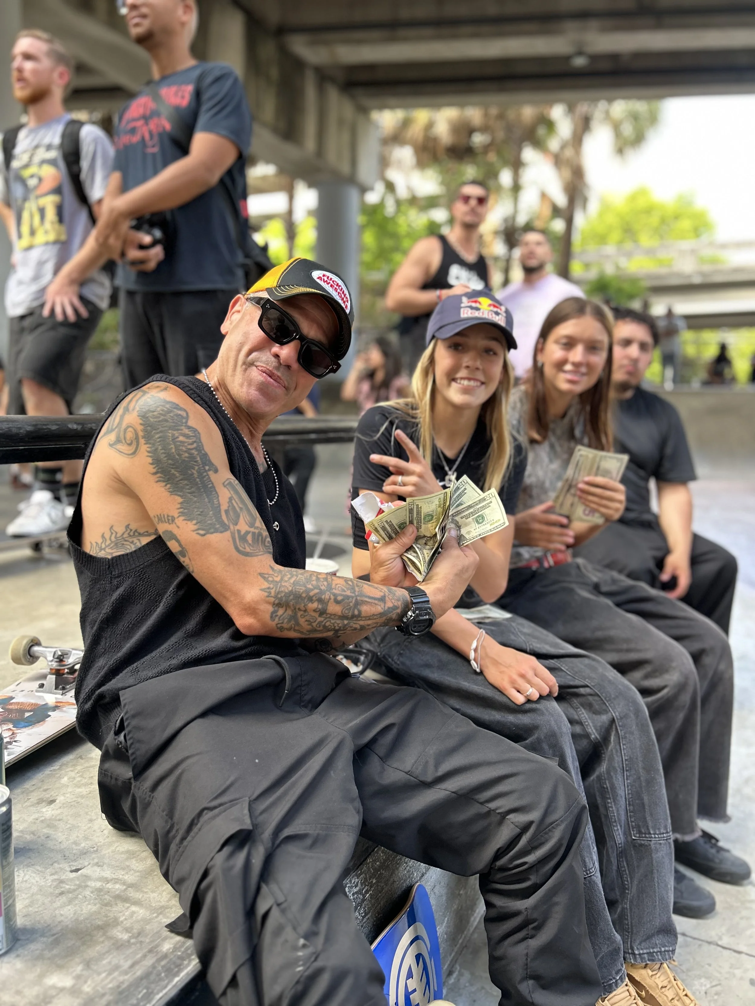 Skam Dust poses spreading a bunch of cash at Lot 11 during a skateboard contest with Chloe Covell during the prize give aways.