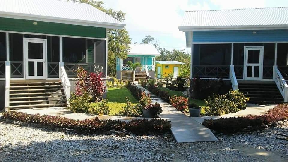 Colorful vacation cottages with porch steps, surrounded by well-kept gardens and a central pathway.