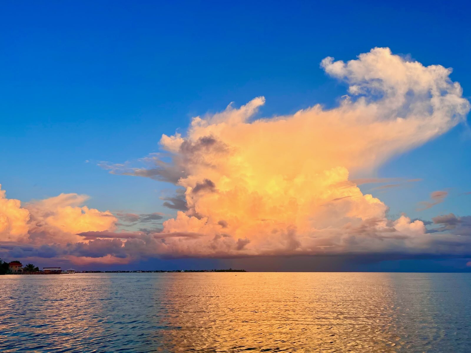 A vibrant sunset over a calm body of water with colorful clouds and a clear blue sky.
