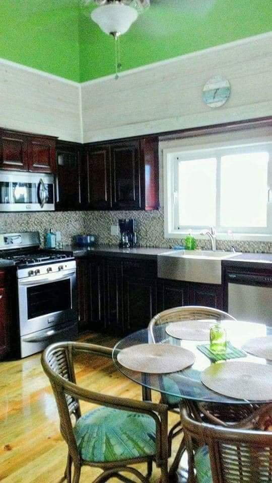 Kitchen with dark wood cabinets, a white farmhouse sink, a window, and a round dining table with four chairs and placemats.