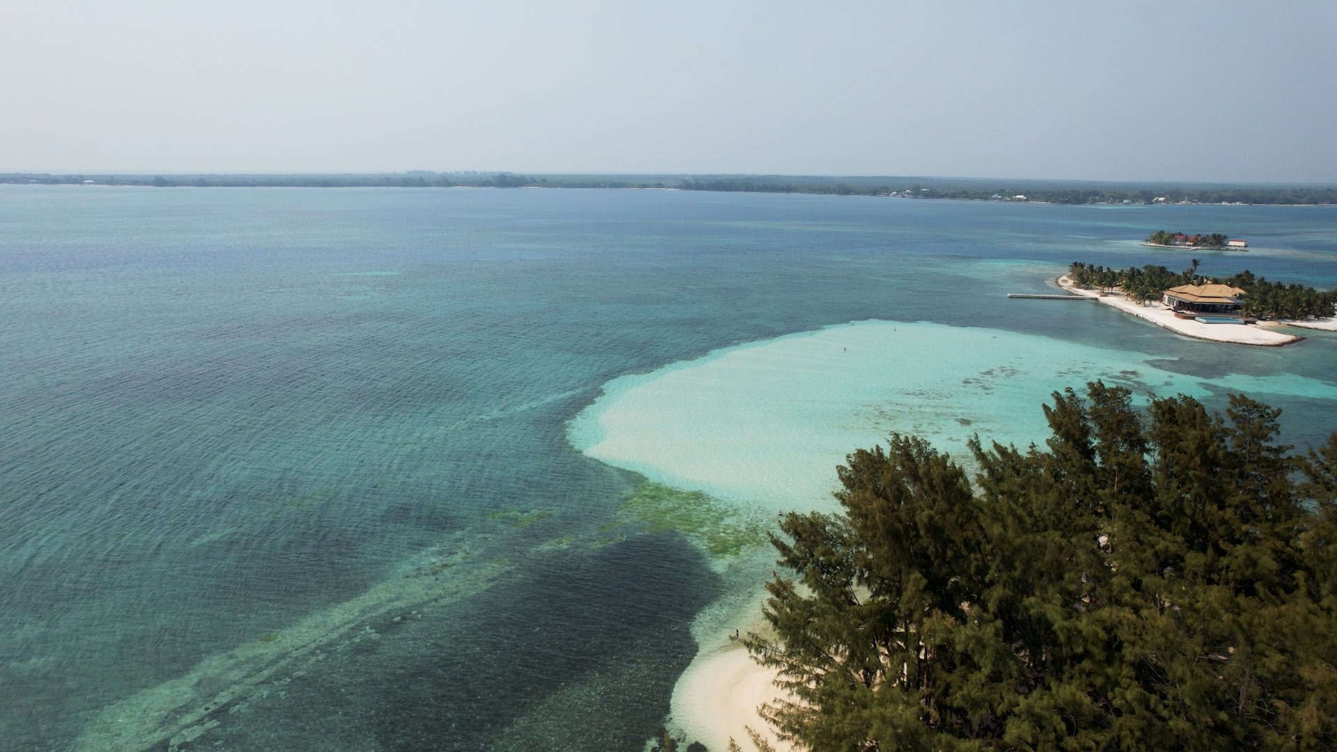 Aerial view of a tropical island with white sandy beaches, lush green trees, and turquoise waters in the ocean.