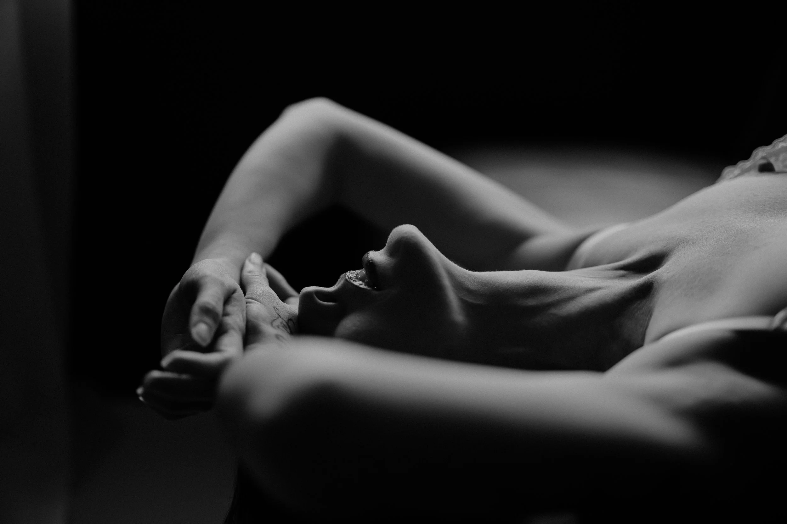 Black and white photo of a woman lying on a couch wearing lingerie.
