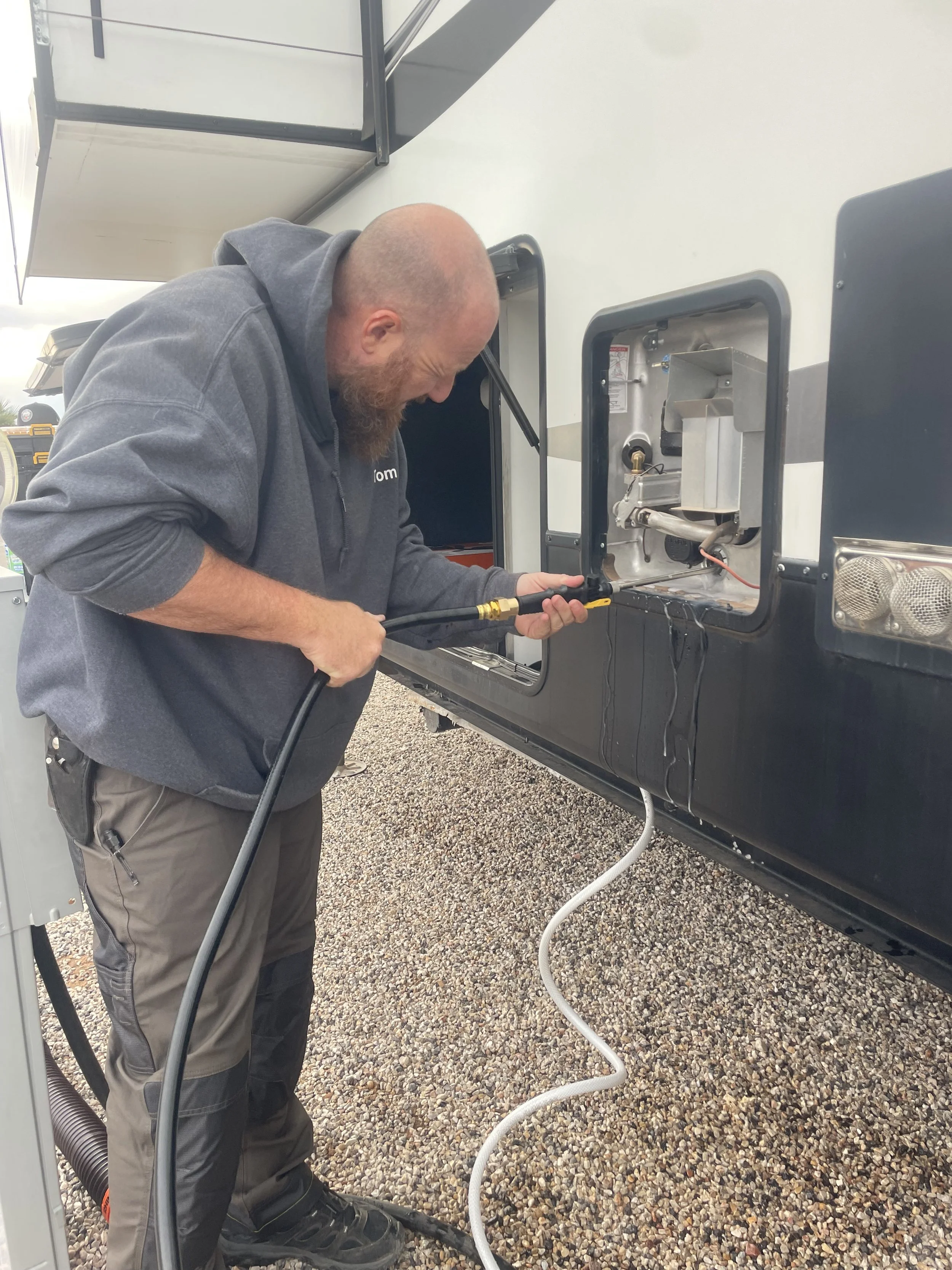 Man with a red beard cleaning an RV water heater.