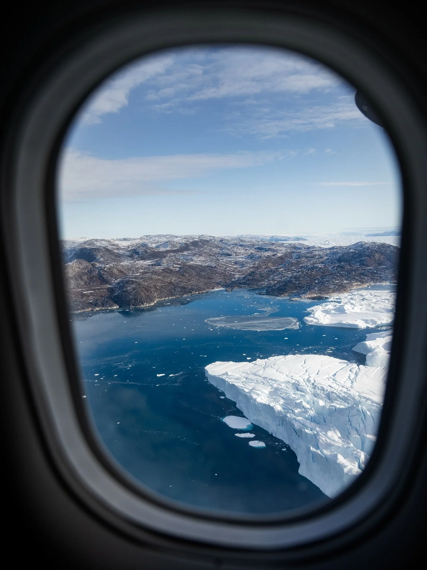 Icebergs, spread out as far as you can see. On land, sled dogs and rugged cliffs remind you how wild Greenland still is 🇬🇱