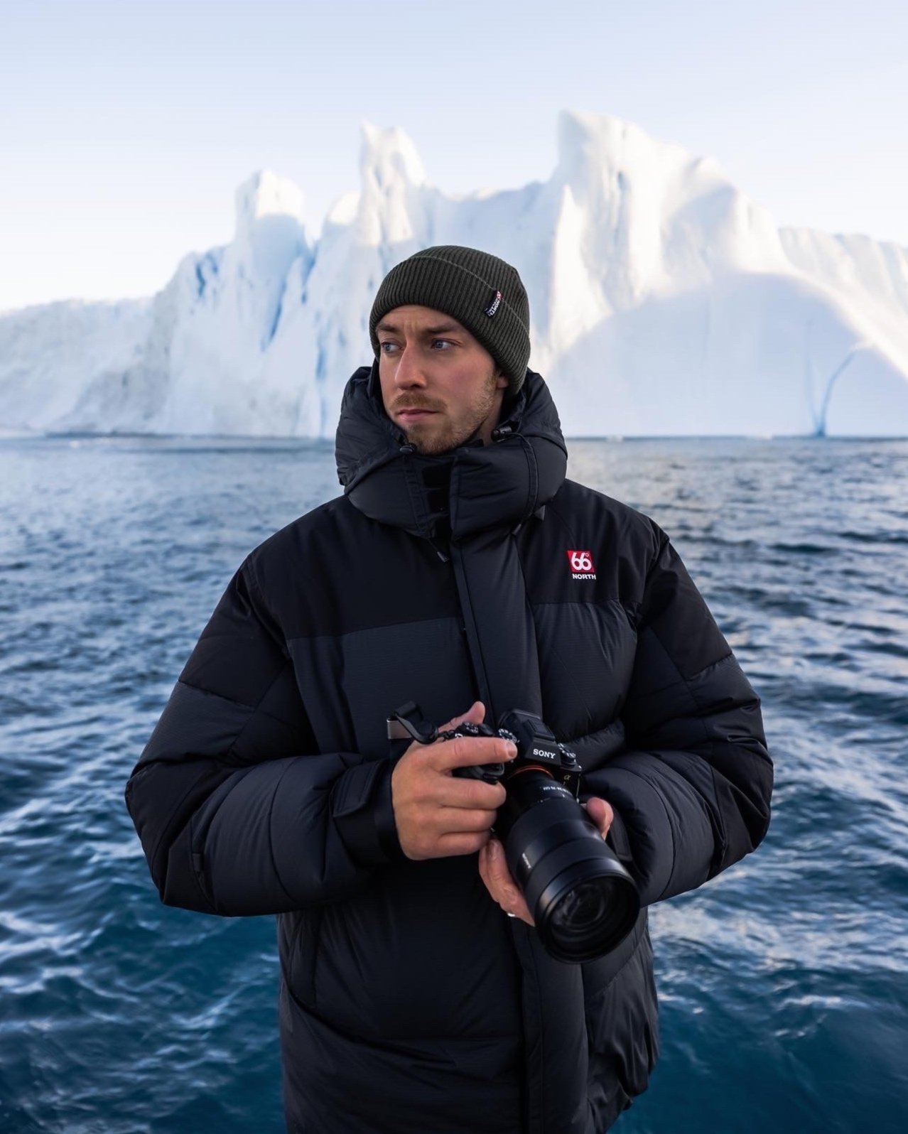 PHOTO OF A MAN HOLDING A CAMERA SAILING AROUND ICEBERGS