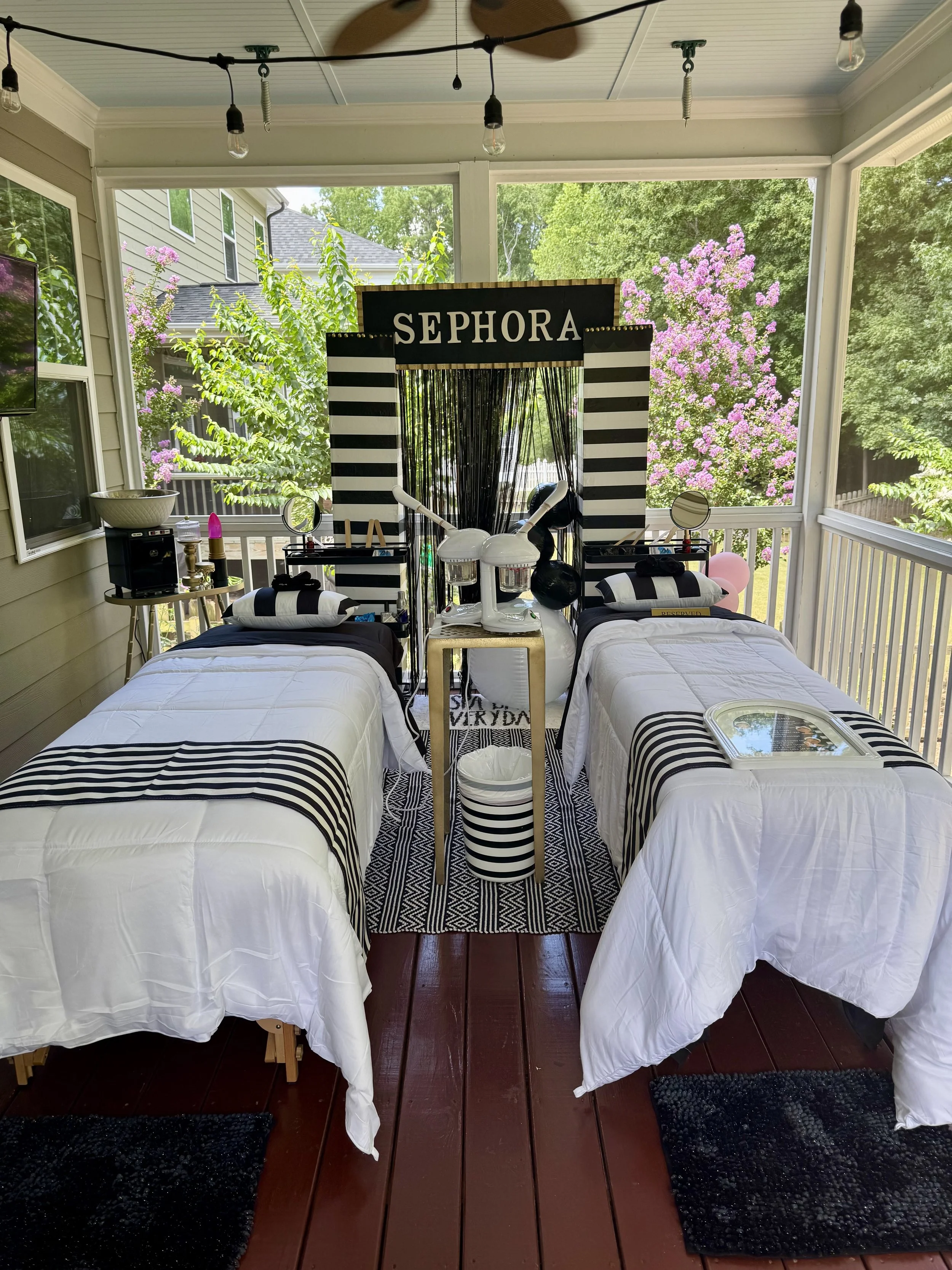Decorative area featuring black and white striped teepees with bows, colorful balloons, pillows with perfume bottle and makeup designs, a striped gift bag, and a rug with the phrase 'SPA DAY FOREVER.'