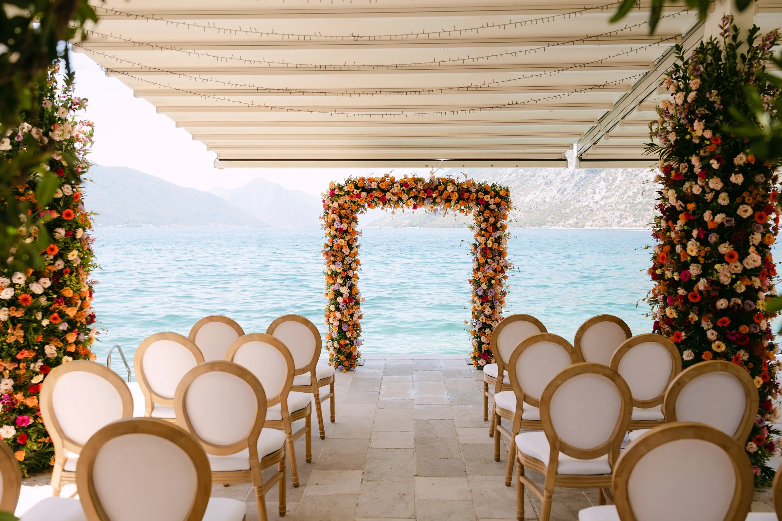 Luxury live flower wedding aisle setup on a dock in Kotor Bay with a seaside and mountains backdrop