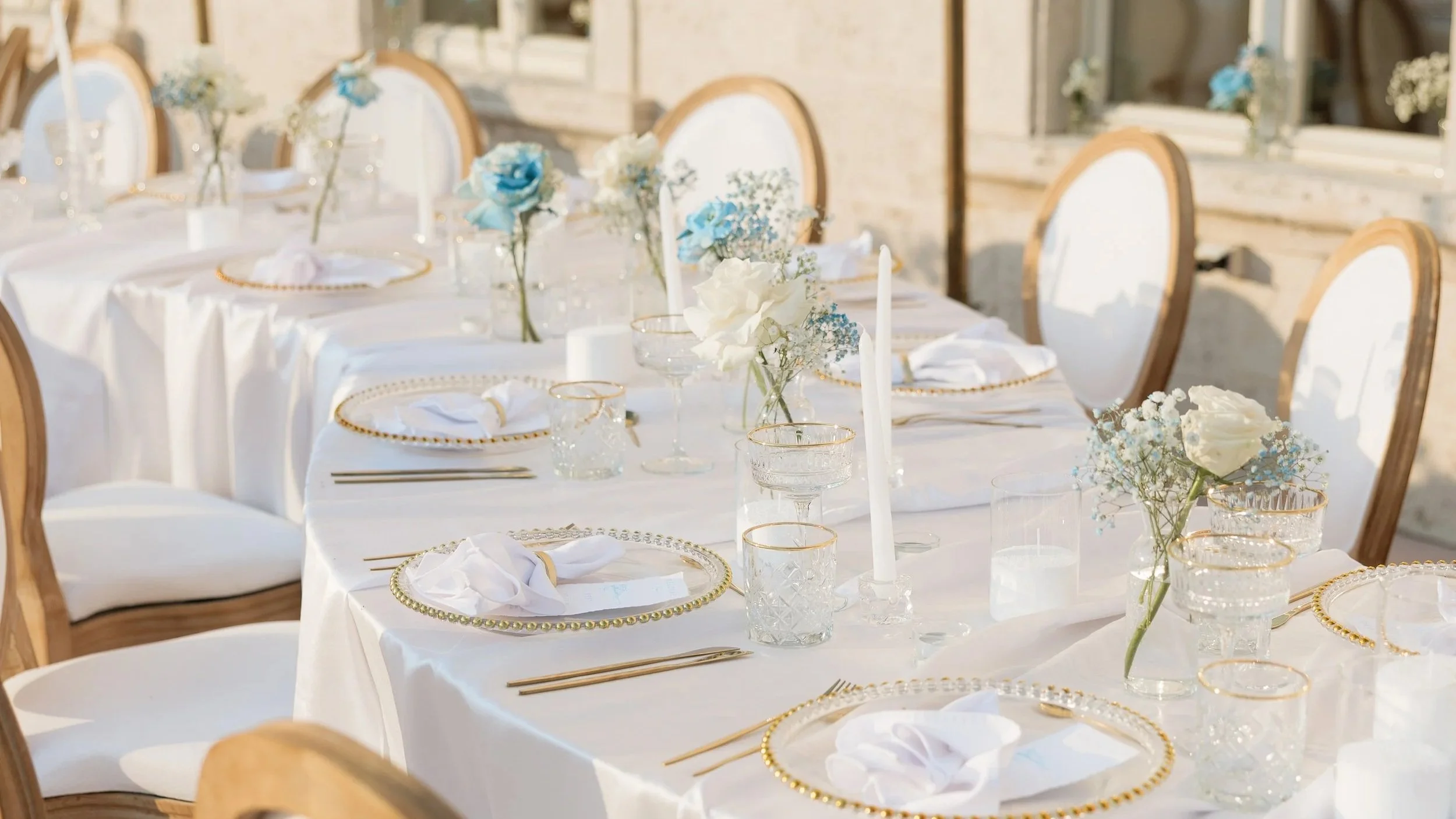 louis chairs serpentine tables with golden cutlery and blue white simple flowers