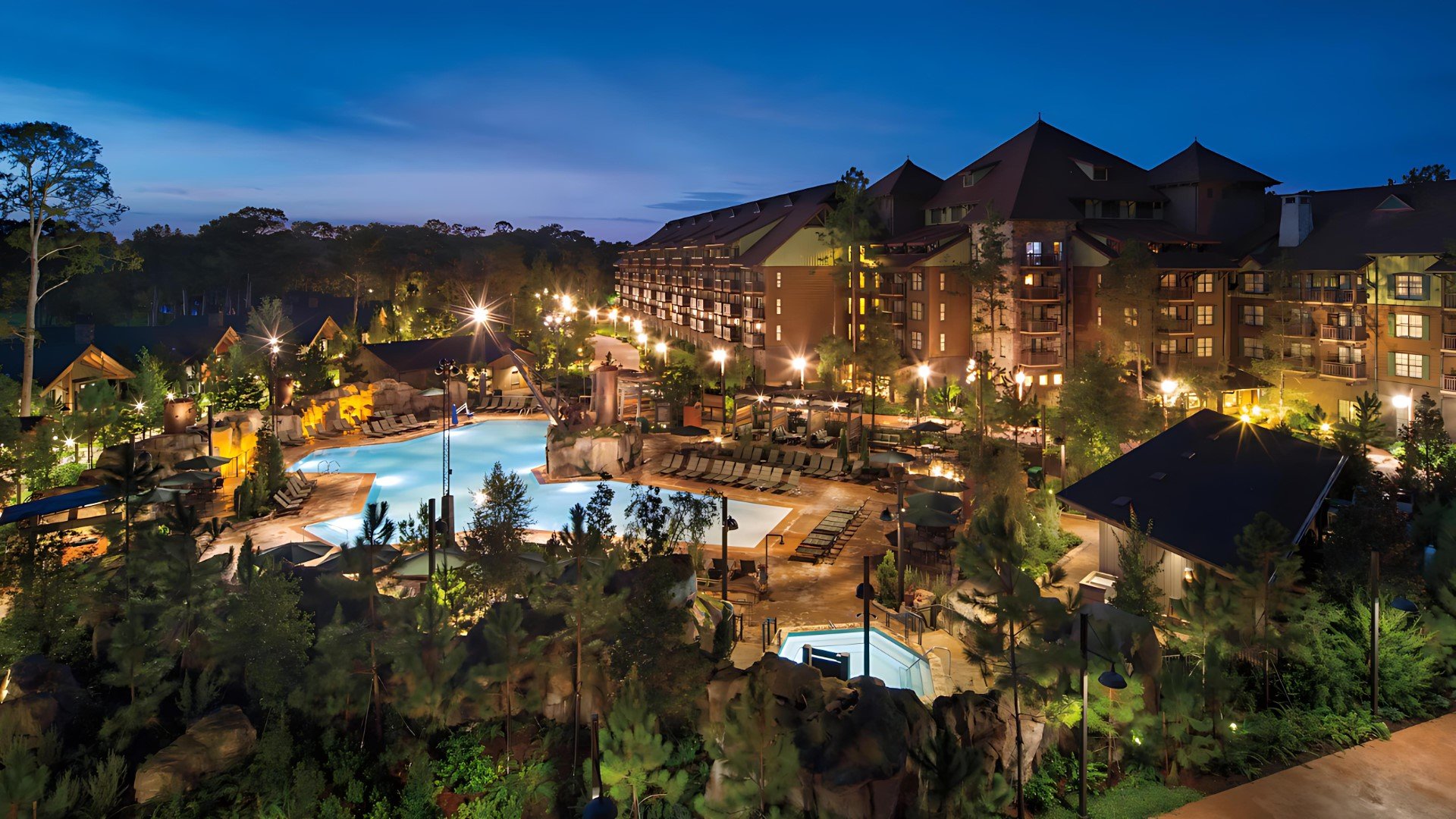 Night view of the Boulder Ridge Resort Hotel with lit outdoor pools, terrace and landscape.