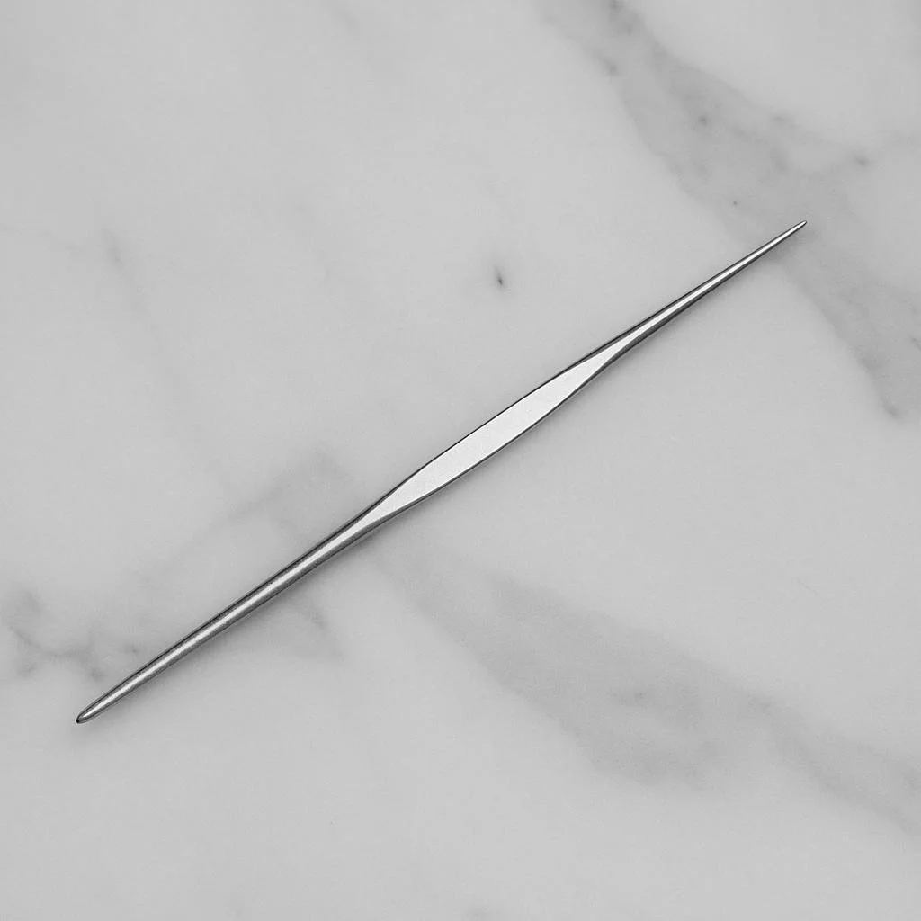 Stainless steel crochet hook on marble surface, used for pulling hair through mesh or extension systems.