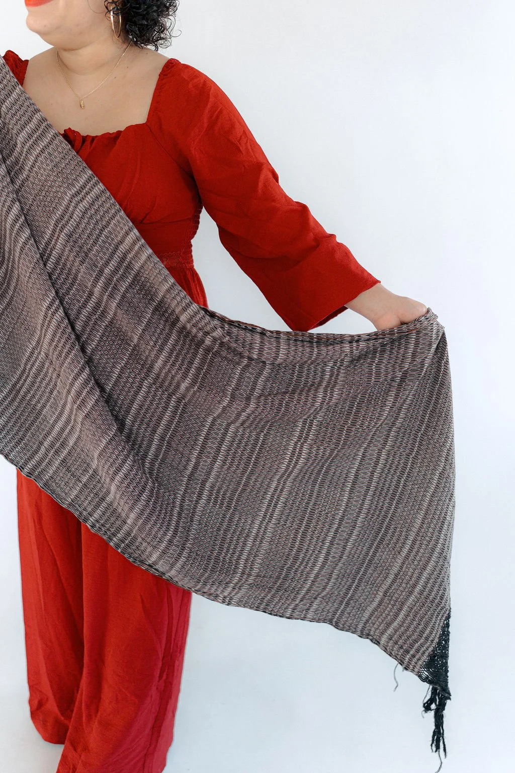 A Spanish speaking doula and sobadora holding a small bottle of oils with a dropper, dispensing a drop into their hand in a dimly lit environment. In Austin, Texas.