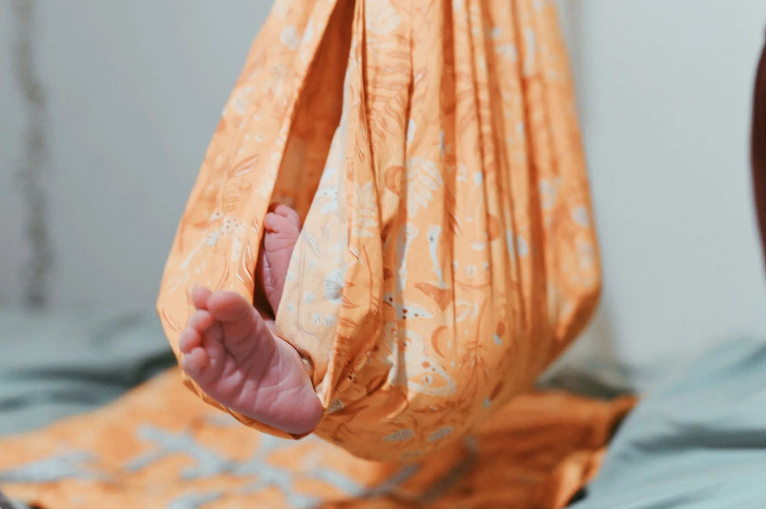 Close-up of a newborn baby's feet peeking out from the sleeve of a scale after a homebirth. In Austin, Texas.
