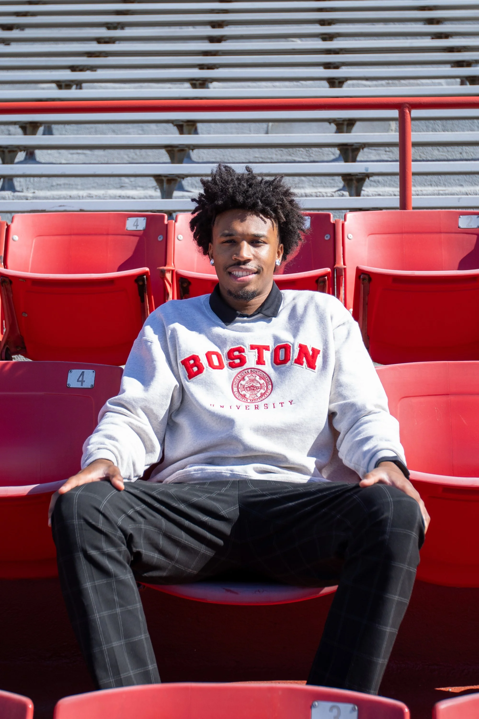 BOSTON, MASSACHUSETTS - APRIL 30: Ethan Okwuosa of Boston University Men’s Basketball poses for a graduation photo seated in the Nickerson Field bleachers on April 30, 2025 in Boston, Massachusetts. (Photo by Max Elliot/Boston University Athletics)