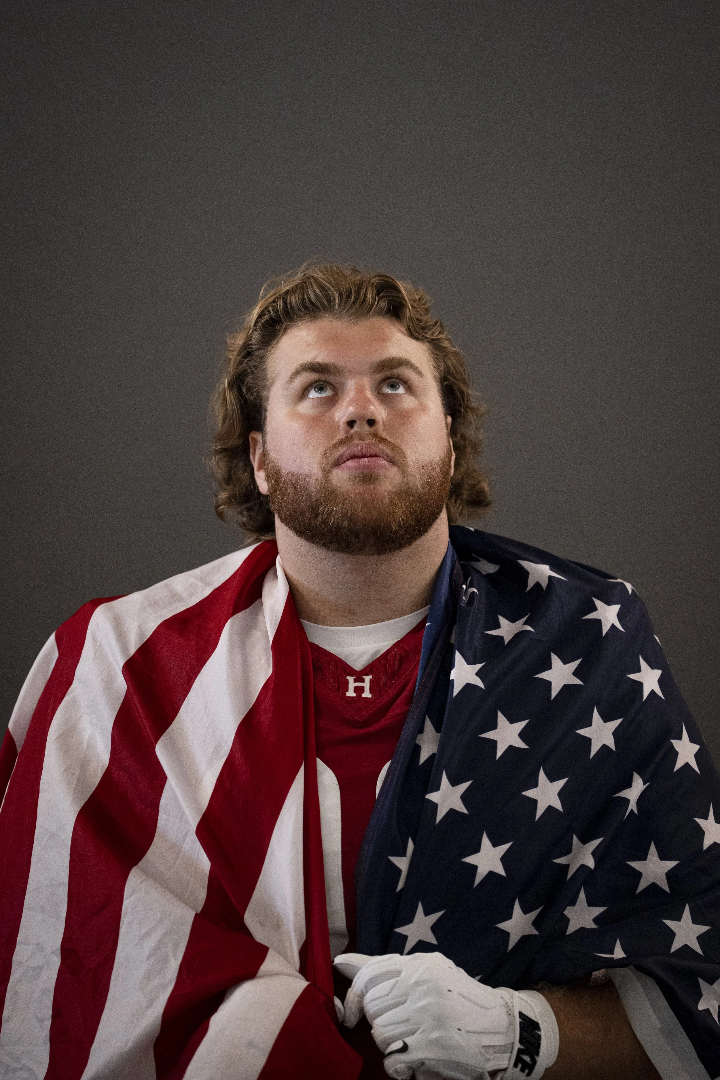 CAMBRIDGE, MASSACHUSETTS - AUGUST 26: Harvard Football's Jake Darling poses for a photo with the American flag during media day on August 26, 2026. (Photo by Max Elliot/Harvard Athletics)