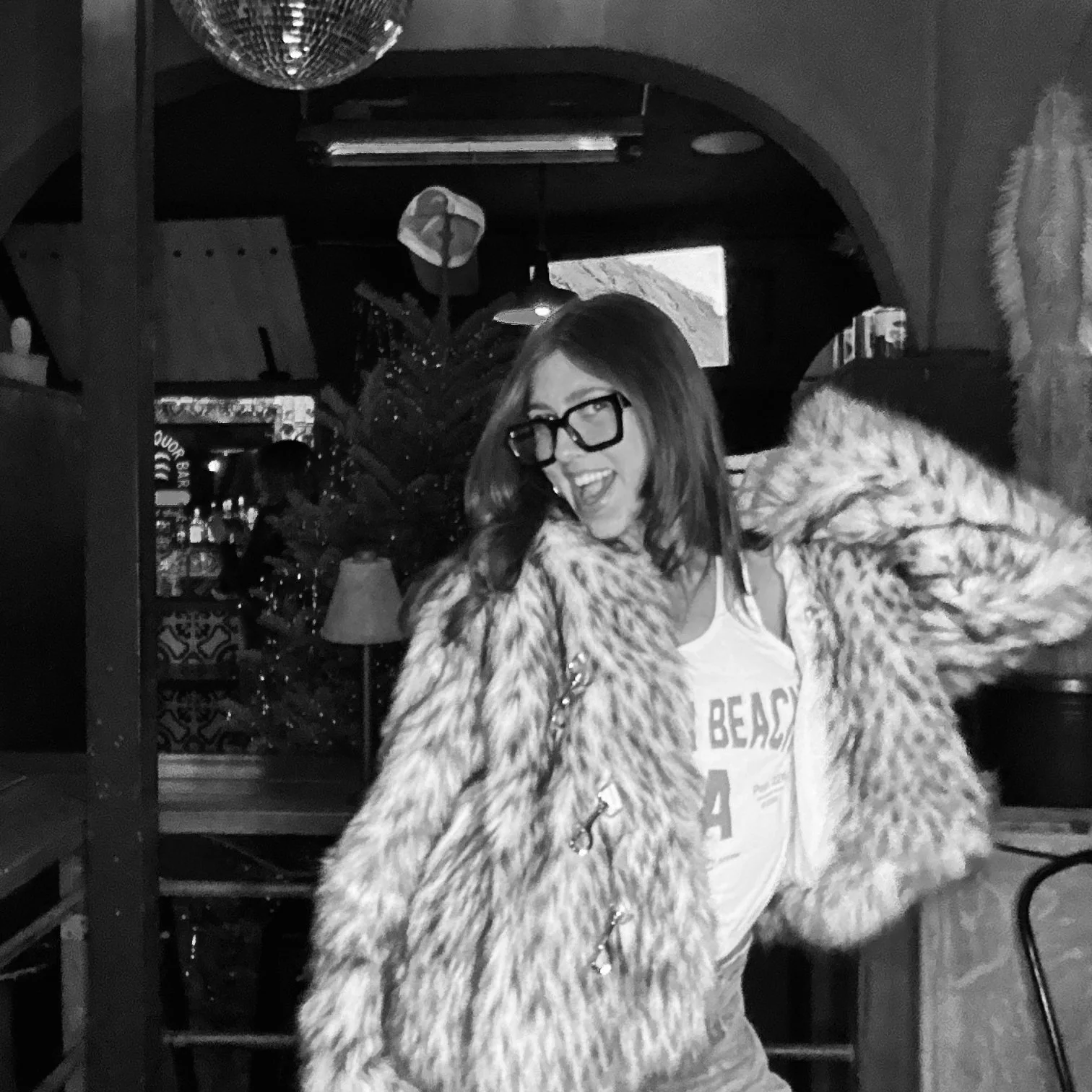 Person wearing glasses and a fur coat, indoor setting