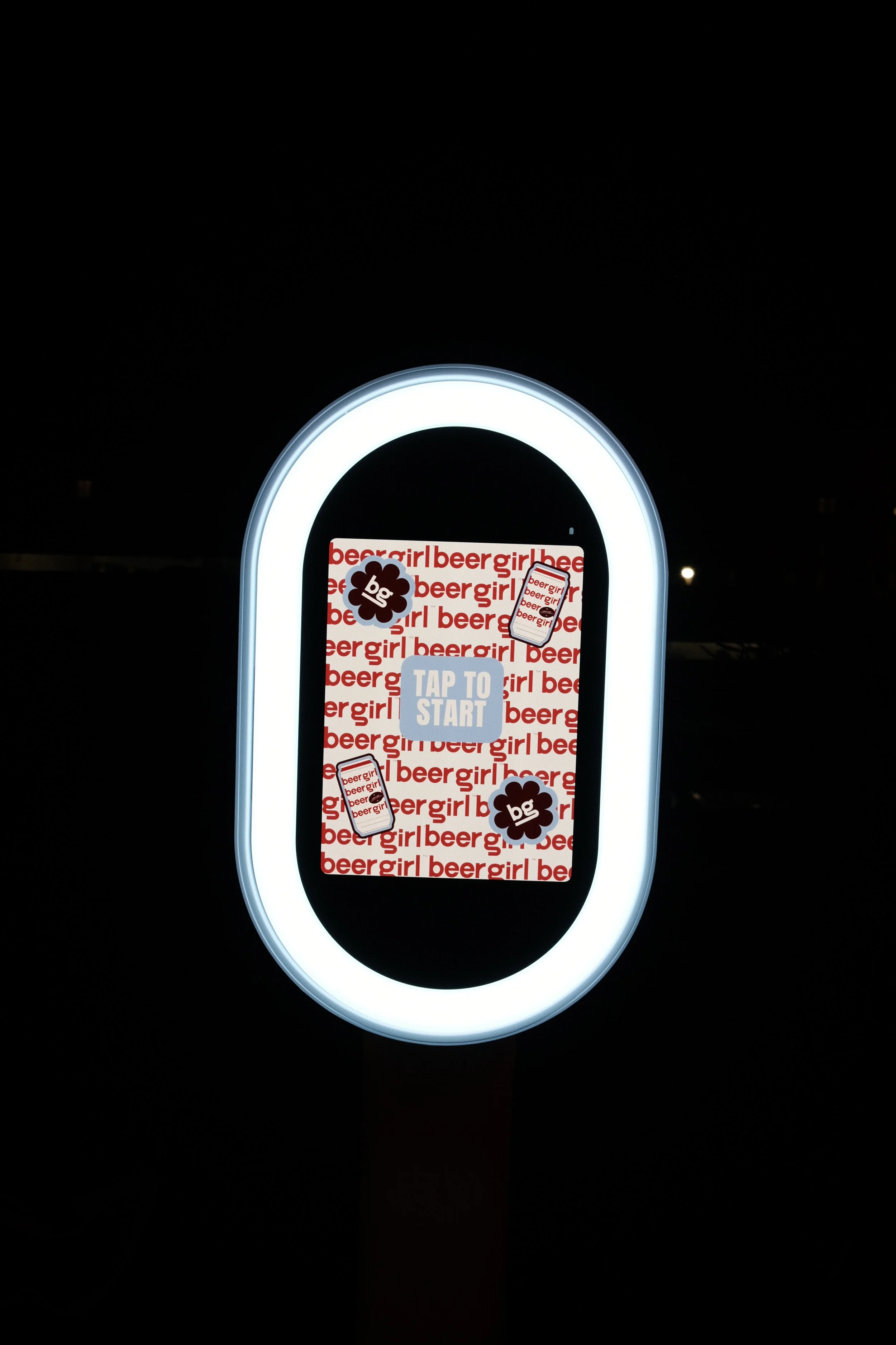 Photo booth touchscreen display with 'Tap to Start' prompt, surrounded by a white LED ring, featuring beer-related graphics and 'beergirl' text.