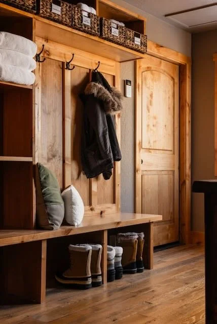 Custom built-in mudroom with ski jacket, snow boots, organized bench seating and labeled storage baskets