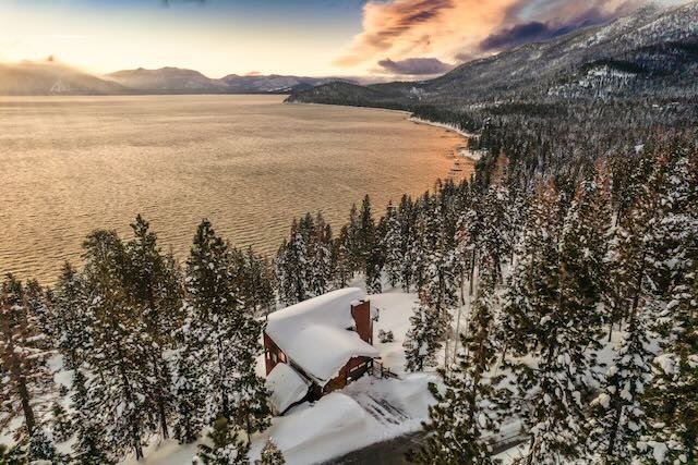 Aerial winter drone view of Ben and Traci's Lake Tahoe property showing lake proximity and snow-covered pine forest at golden hour