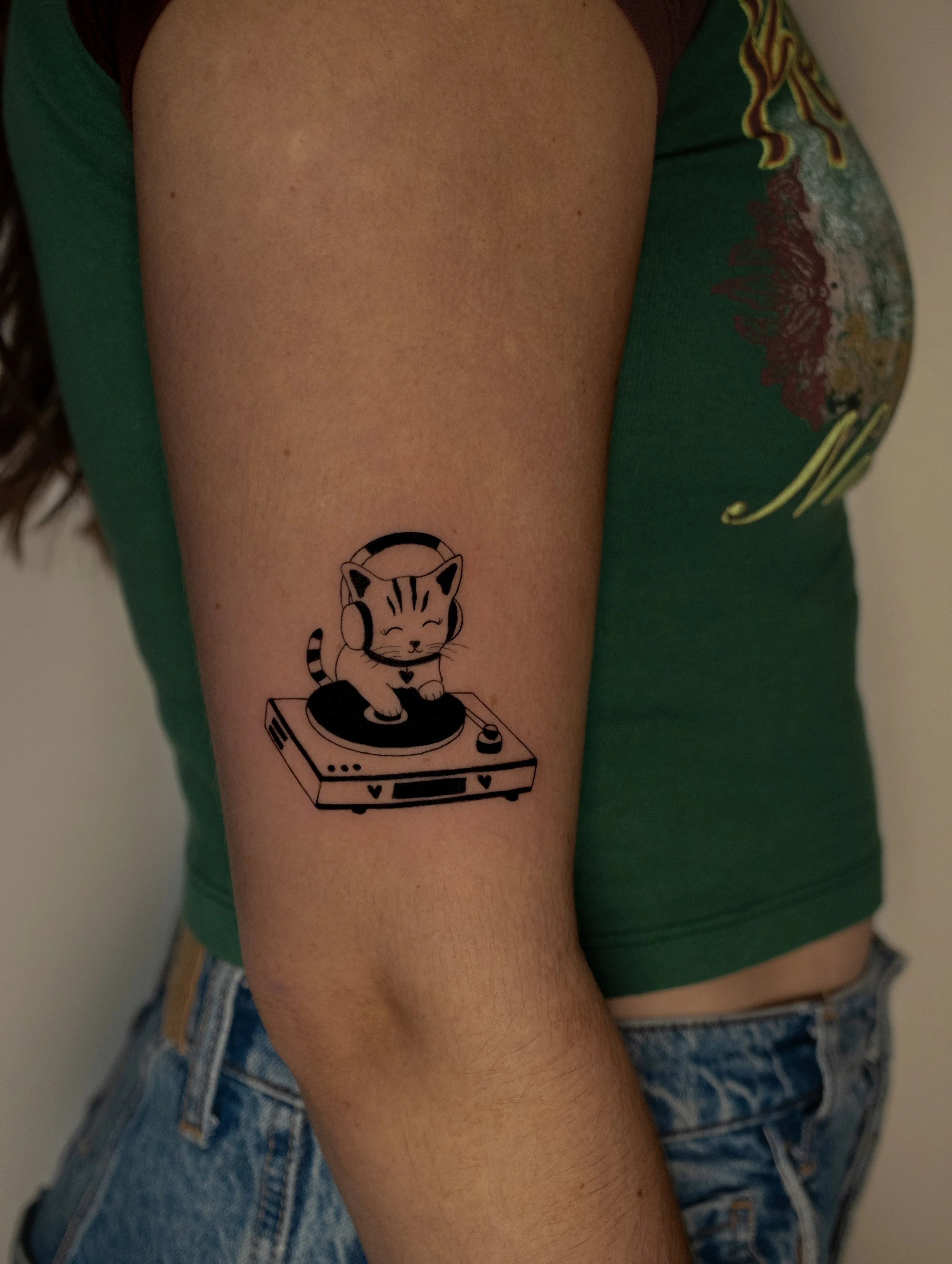 Cute kitty DJ and mixtables tattoo in a fine line art style by Erica Inagaki in Broomfield Colorado.