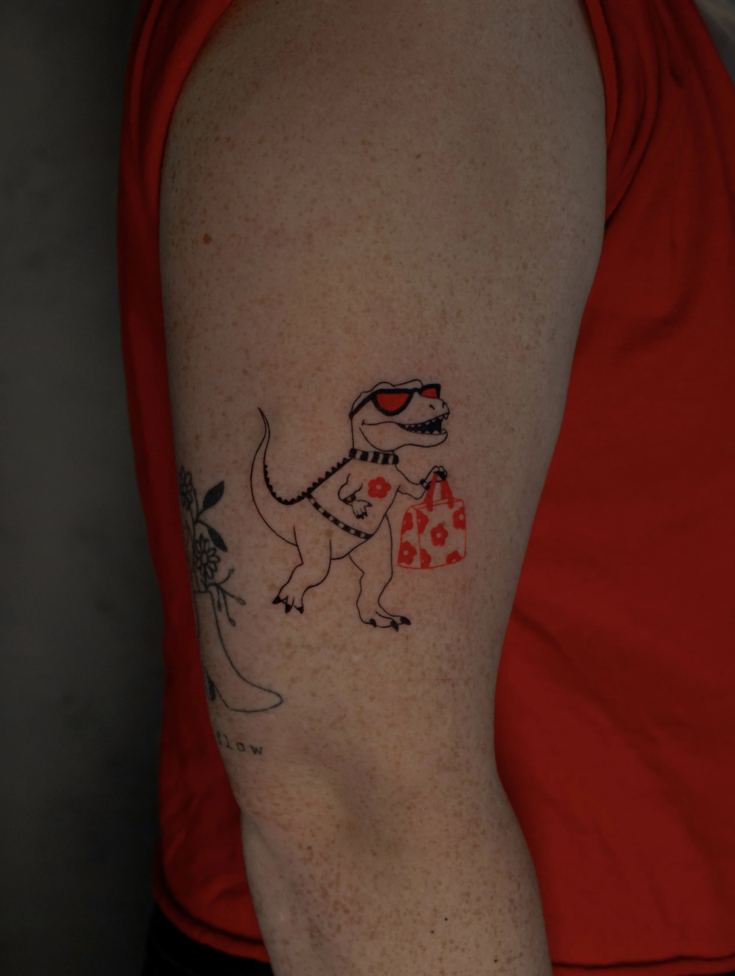 Cute Dino Diva tattoo - A small T rex tattoo with designer clothes, bags and sunglasses in a fine line art style created by Erica Inagaki in Boulder Colorado