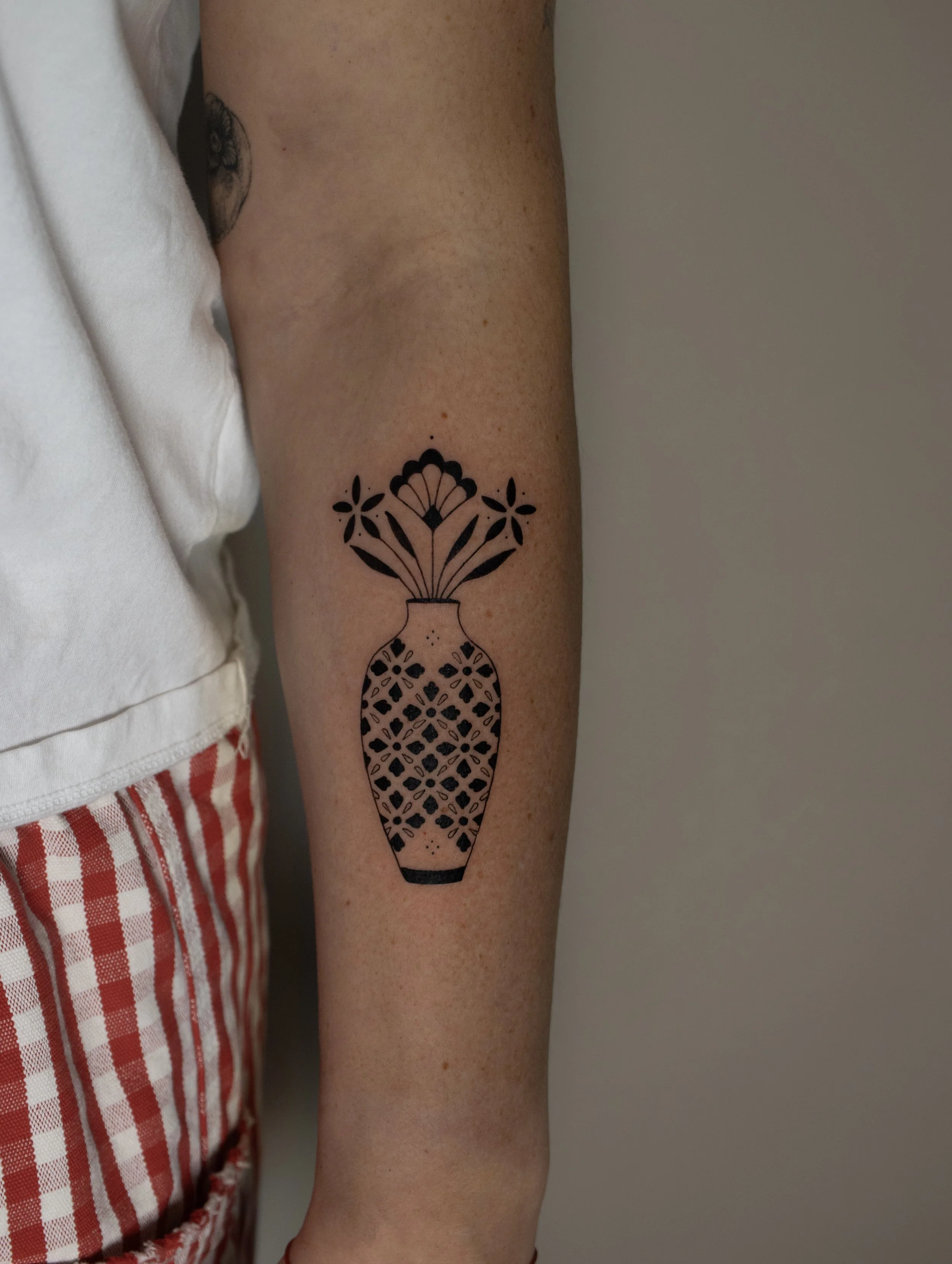 Plants and vase fine line tattoo with a geometric pattern - small tattoos created by Erica Inagaki in Denver Colorado.