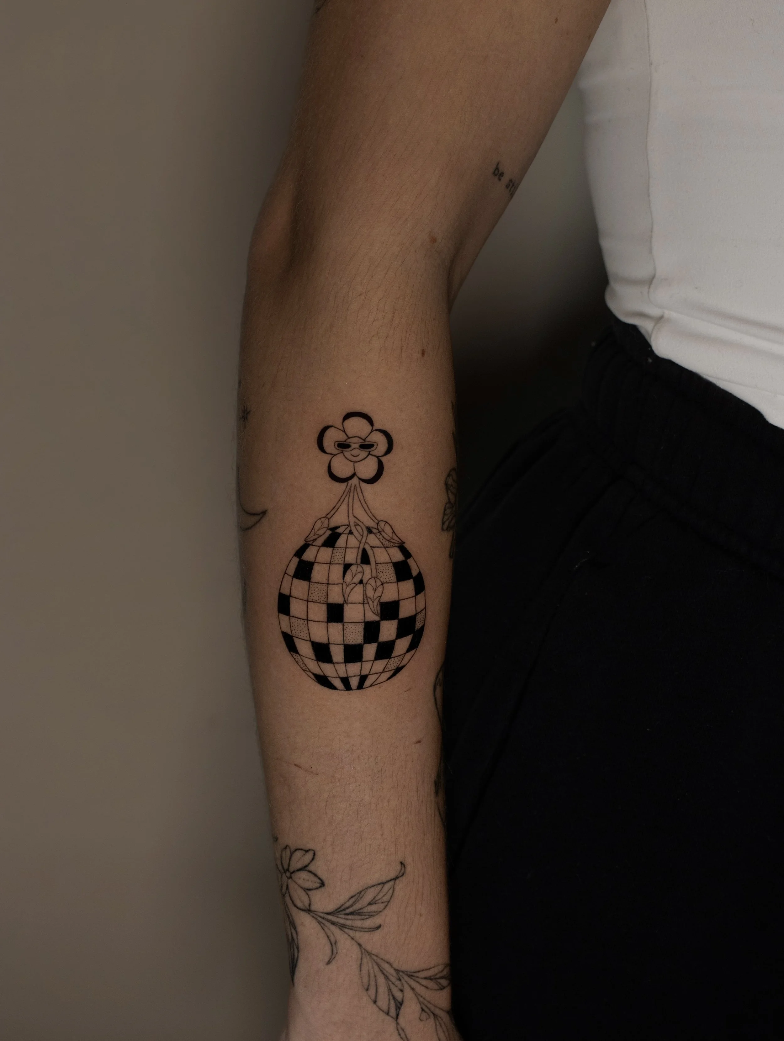 Cute Disco ball and flower tattoo in a fine line art style - small tattoo on the arm for women - created by Erica Inagaki in Boulder Colorado.