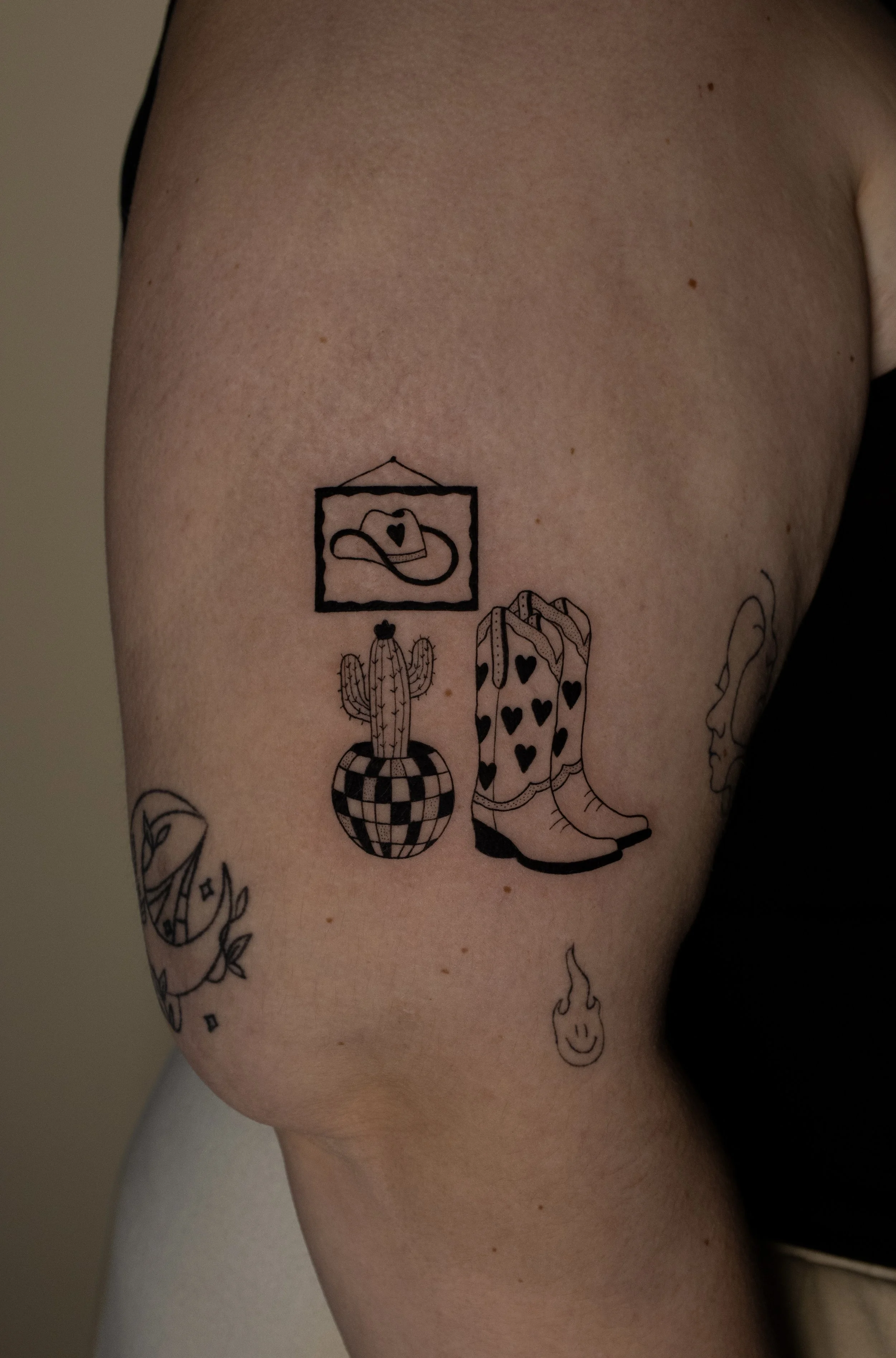 Western tattoo including cowboy boots, hat, cactus and disco ball - created in a minimalist fine line style by Erica Inagaki in Arvada Colorado