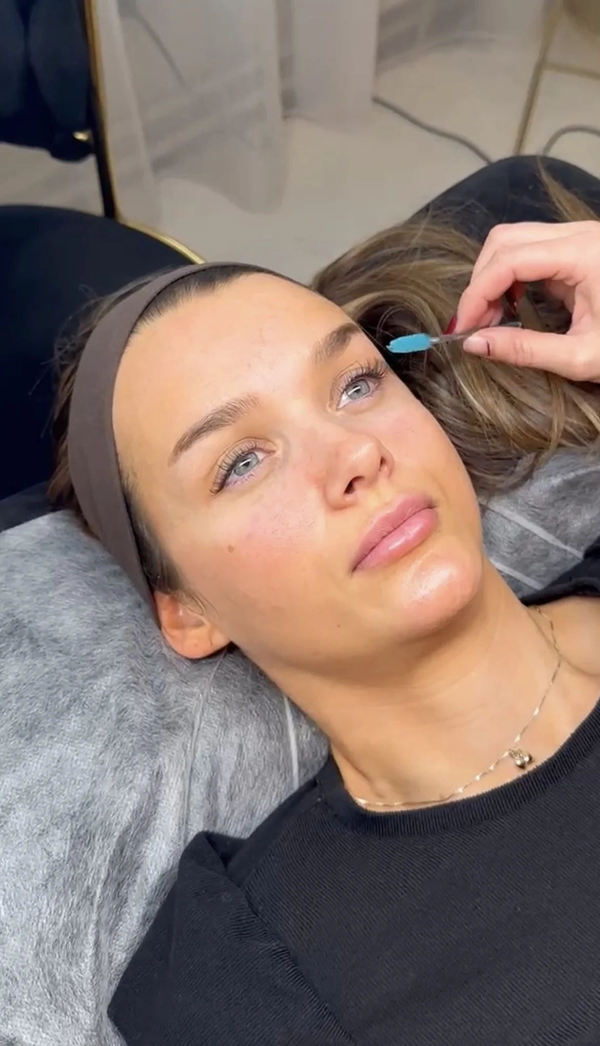 Kvinne ligger på en sofa og får injeksjon i øyet, sannsynligvis for kosmetiske formål.