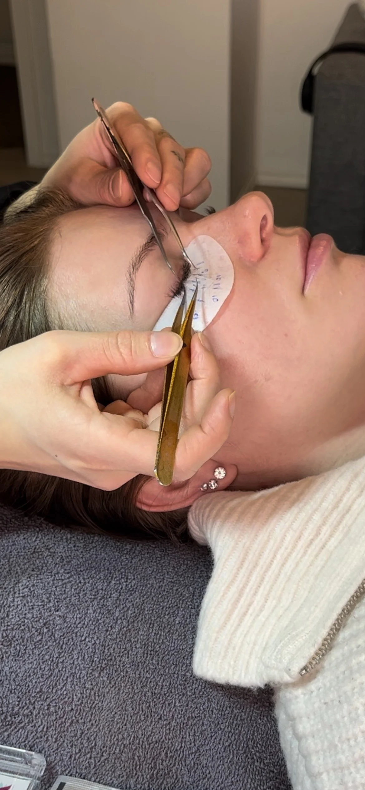 En person får en øyebrynsblekning behandlet. Dette skjer med en pensel og pinsett i en skjønnhetssalong.