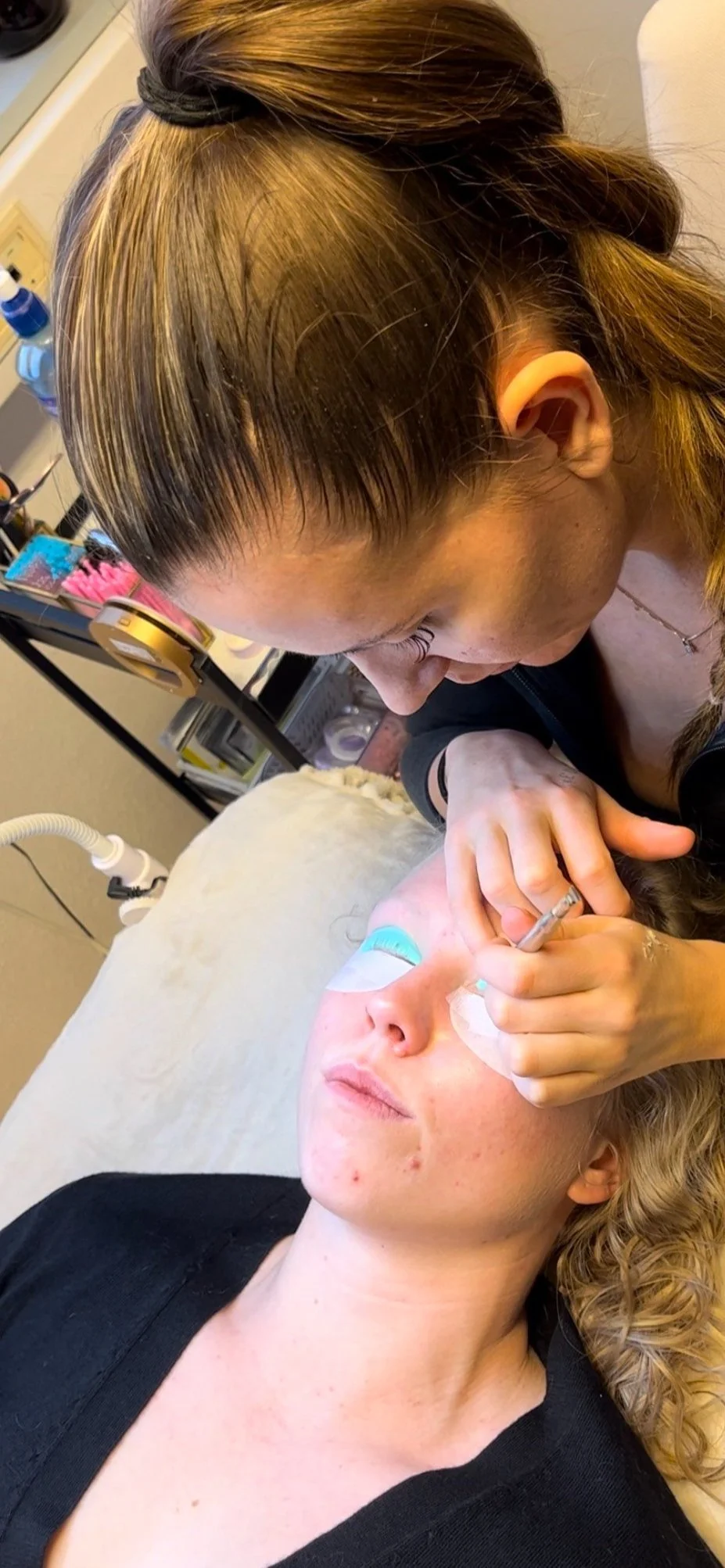 Kosmetisk behandling der en kvinne får øyelokkbehandling med en profesjonell som bruker en nål.