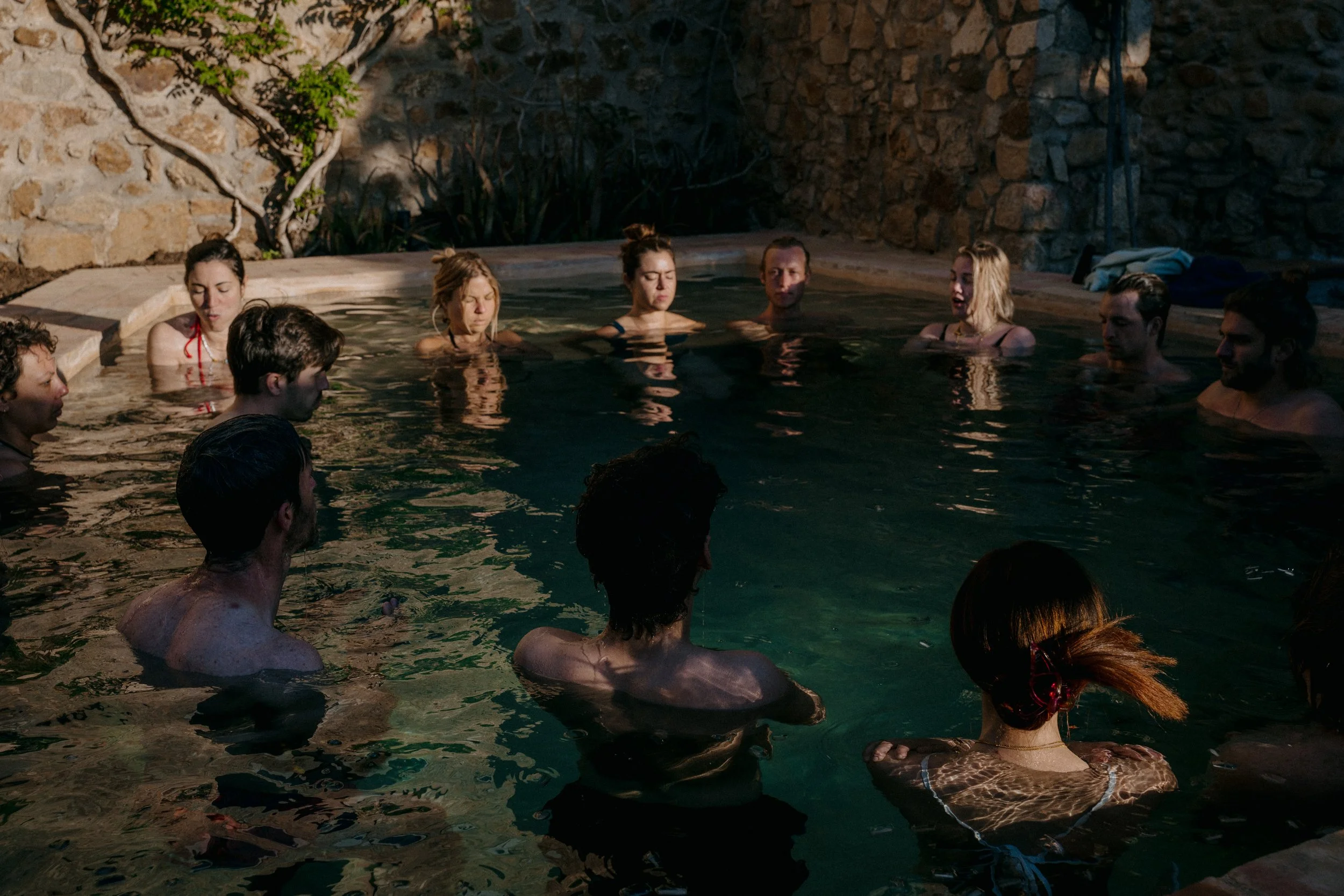 Group connecting in a circle in an outdoor pool during a Held Retreats wellness retreat