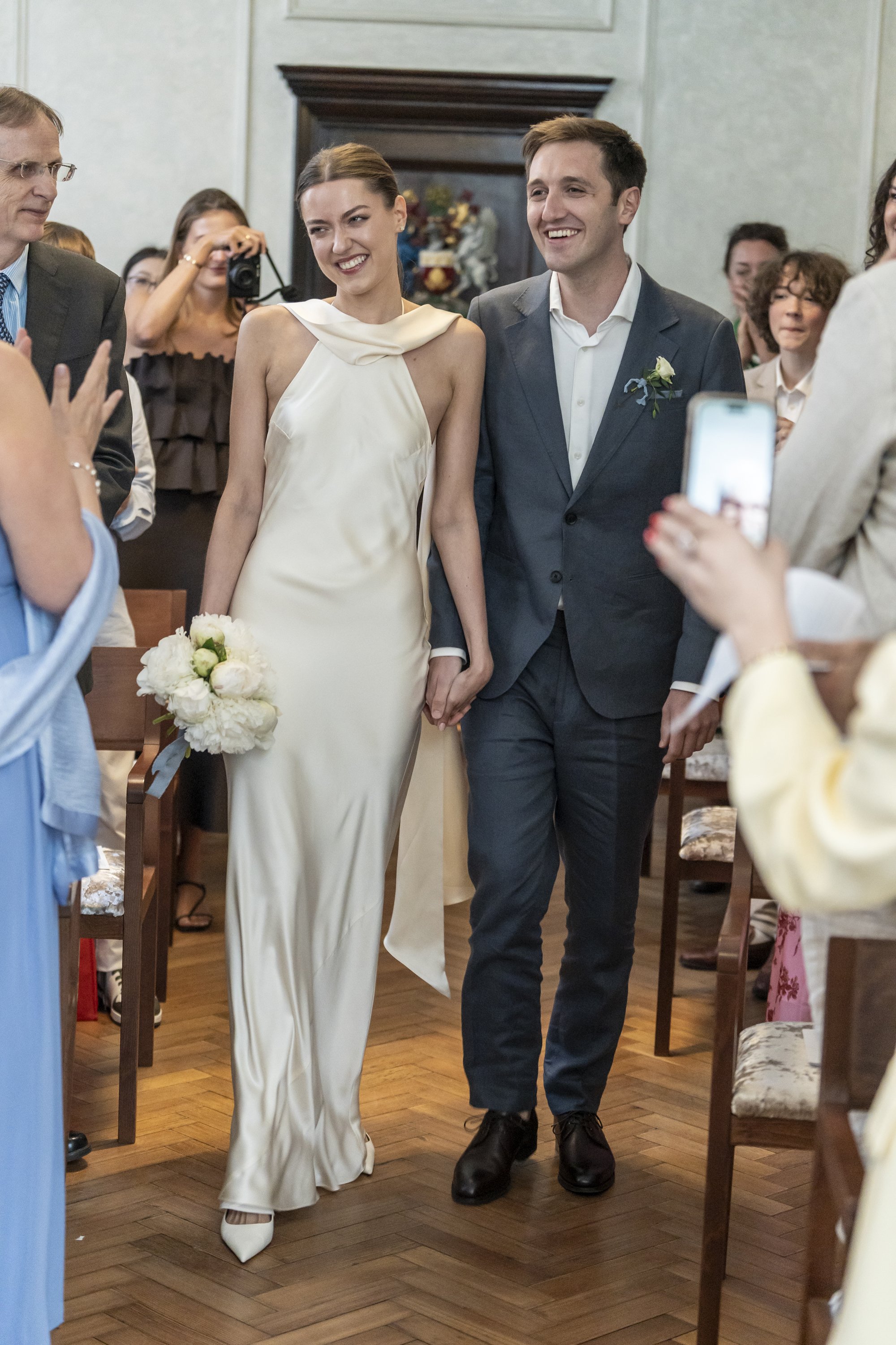 Wedding ceremony in rustic barn with couple kissing and guests applauding.