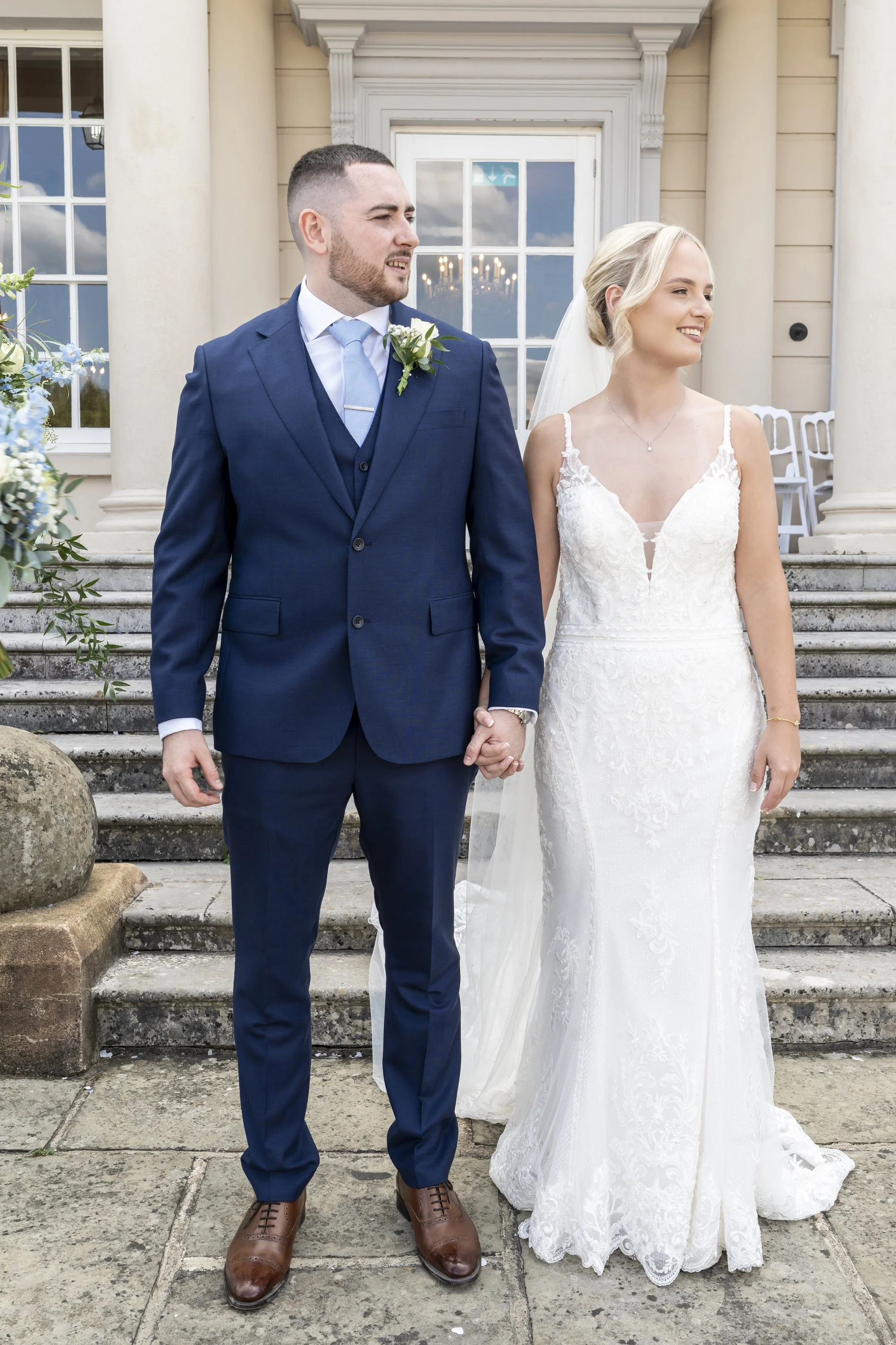 Wedding ceremony with couple exchanging rings in church, officiant holding a book and microphone, guests seated in the background.
