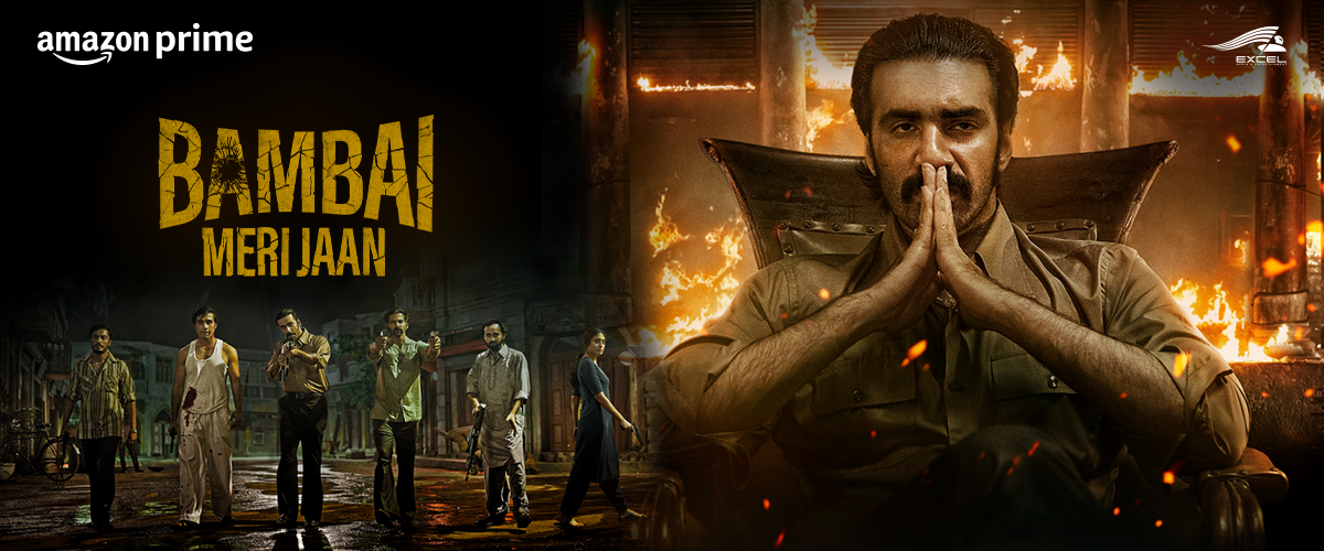 Poster for the movie 'Bambai Meri Jaan' featuring a man in a police uniform sitting with hands in a prayer position in front of a background of a burning building, with a team of people walking on a wet street and the 'Amazon Prime' logo.