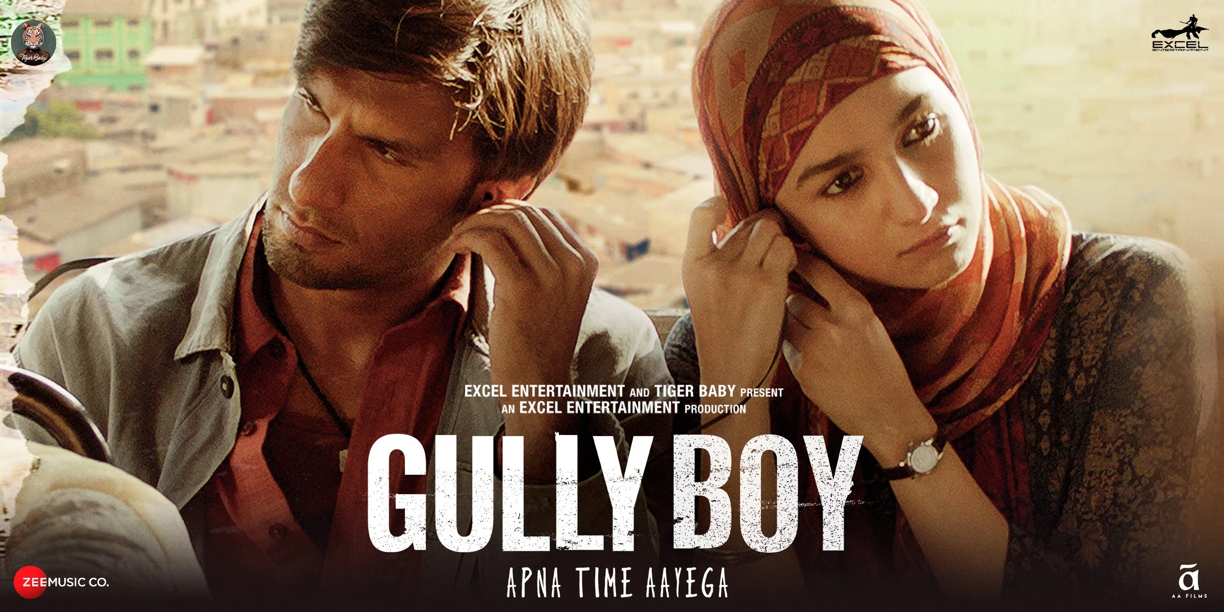 A man and a woman sitting closely together with a cityscape in the background, both holding headphones to their ears, as part of a promotional poster for a film titled 'Gully Boy'.