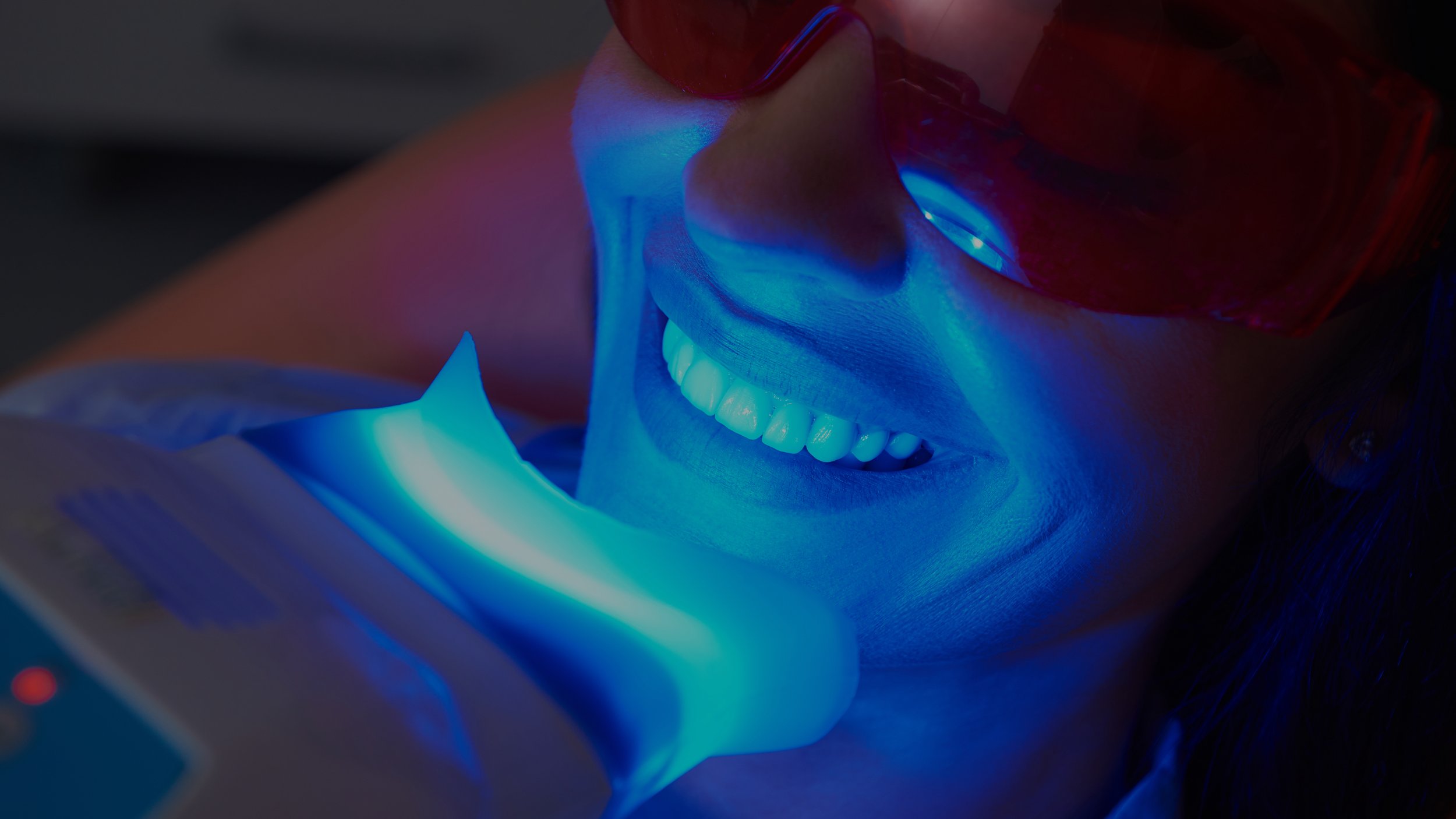 Client receiving professional teeth whitening with LED light for a brighter smile at Bronze Couture in Kalamazoo, Michigan.