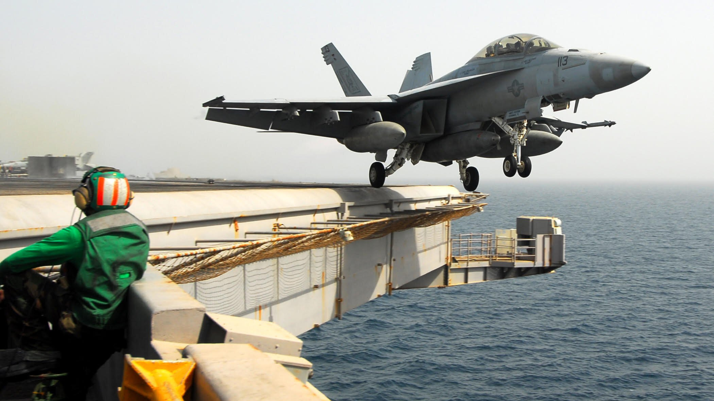 A US Navy fighter jet launching off a carrier deck demonstrating team cohesion at its best