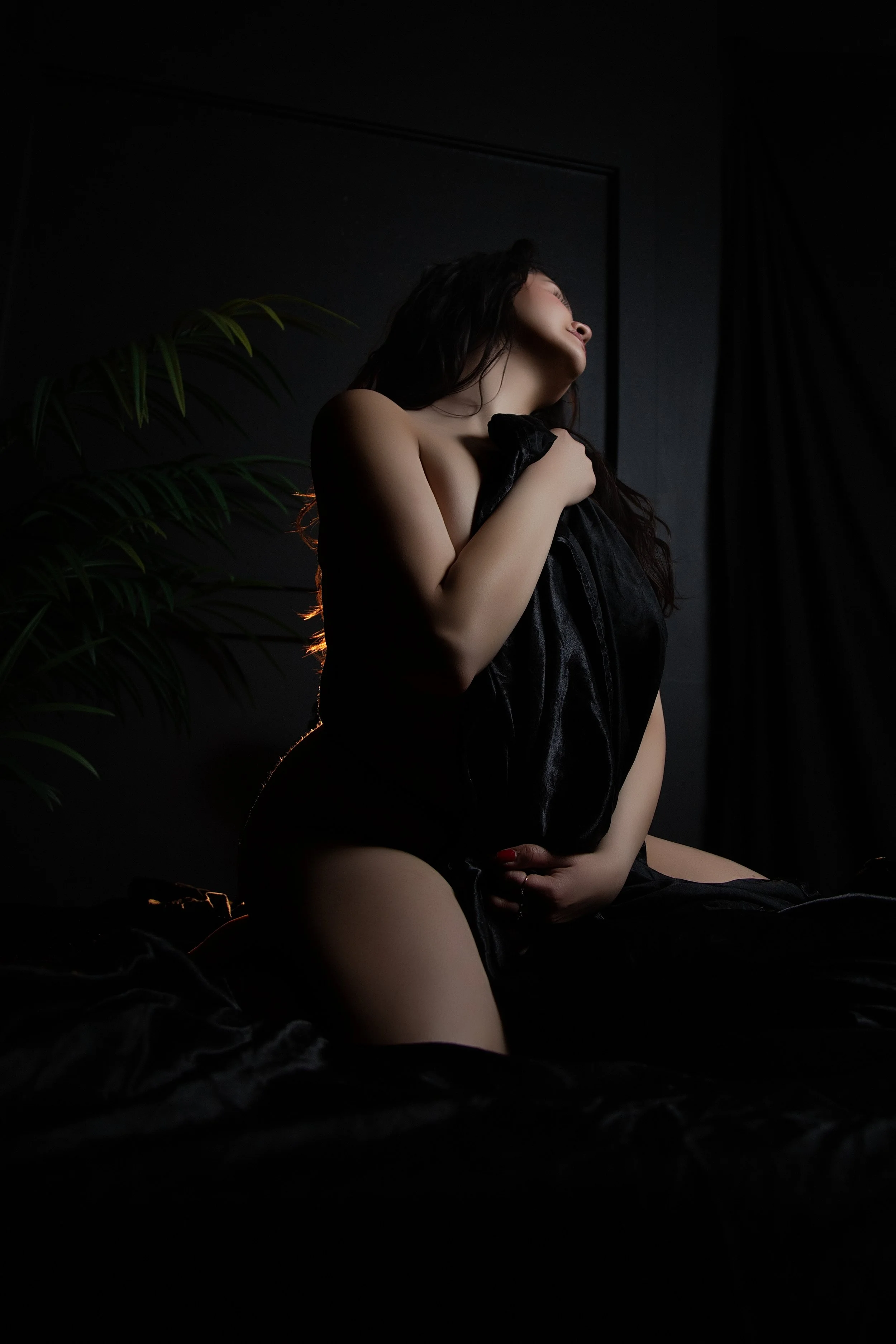 Calgary Boudoir Photography plus sized woman draped in fabric in a dark room