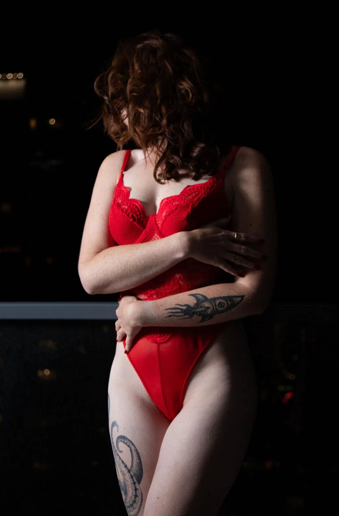 A thin woman in a red body suit outside for a downtown calgary boudoir photo shoot