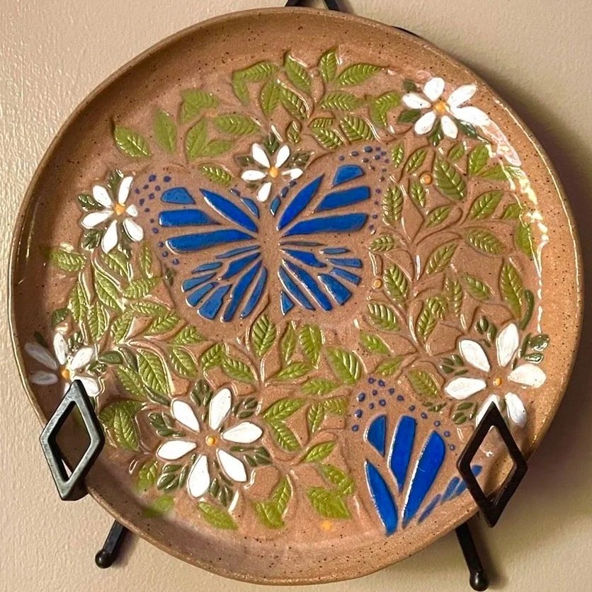 3 handmade Clay sunflowers in a ceramic basket placed on a stone surface with a stone wall background.