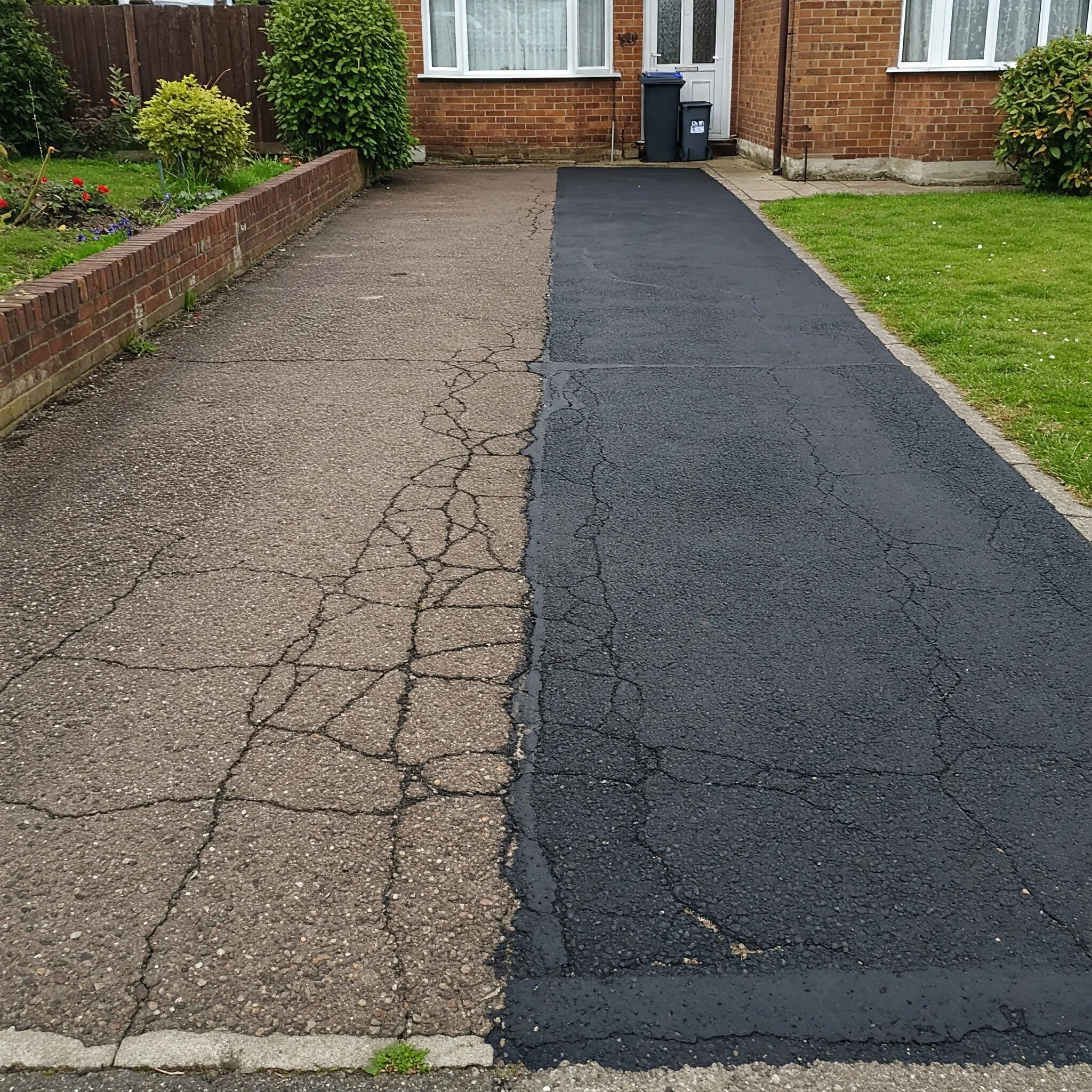 A driveway with the left side old, cracked concrete and the right side newly resurfaced black asphalt.